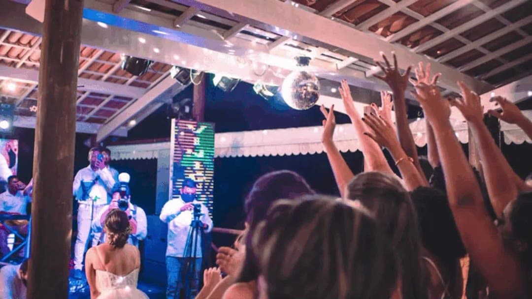 Convidados com os braços para cima na pista de dança