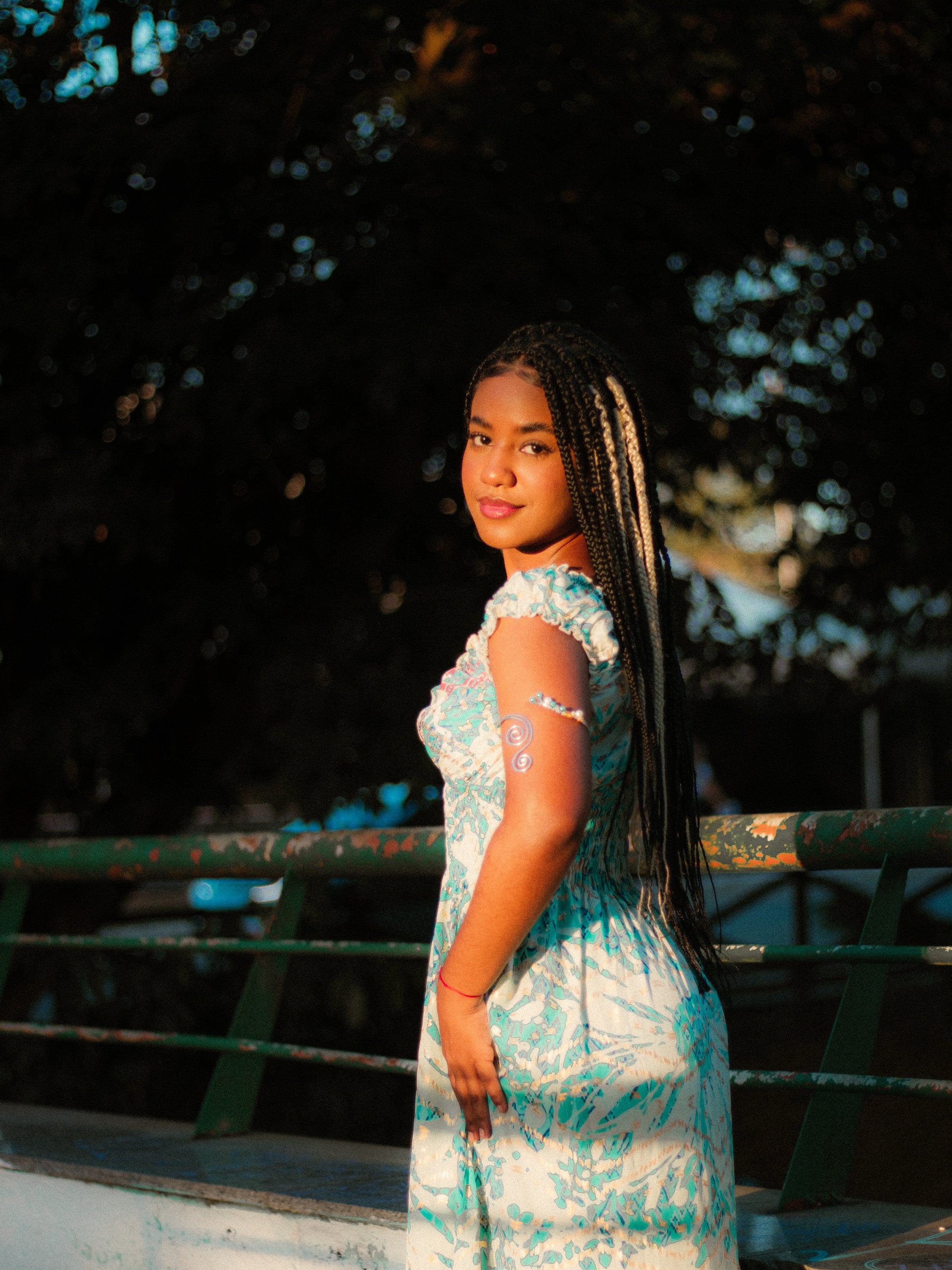 Sentada na mureta de grade verde, na luz de fim de tarde, ensaio individual