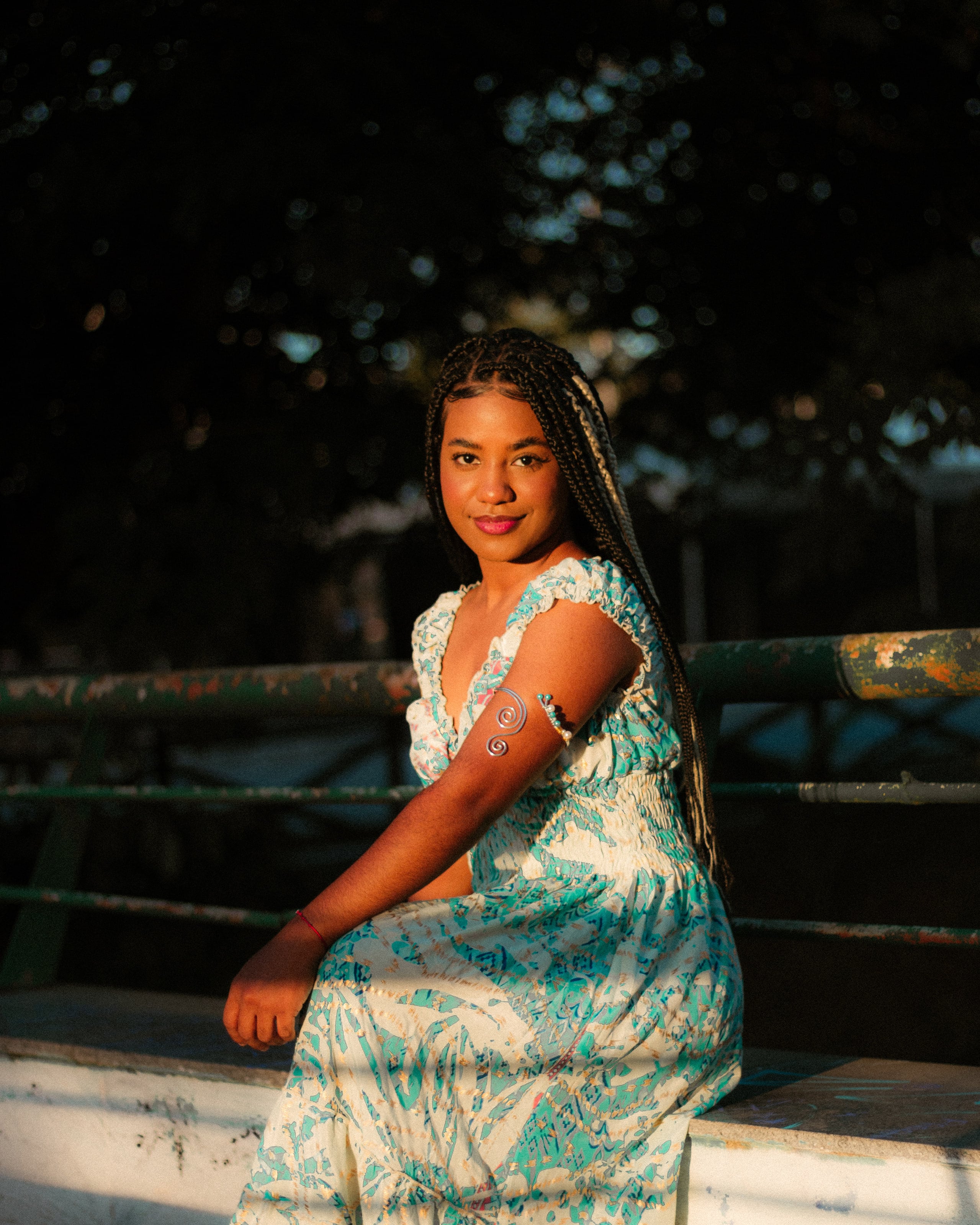 Sentada na mureta de grade verde, na luz de fim de tarde, ensaio individual