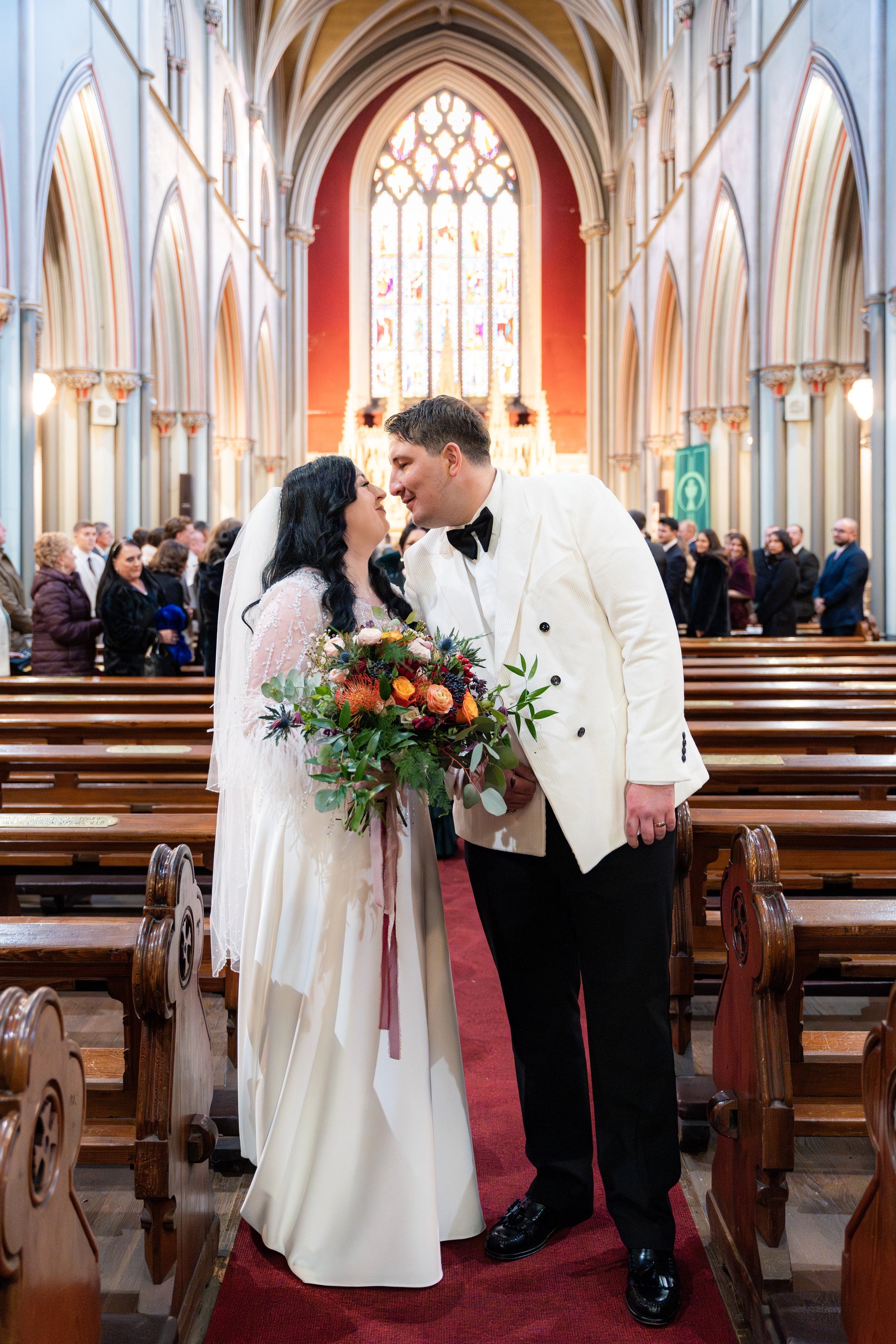 Beijo no corredor entre os bancos de madeira, casamento de C & S