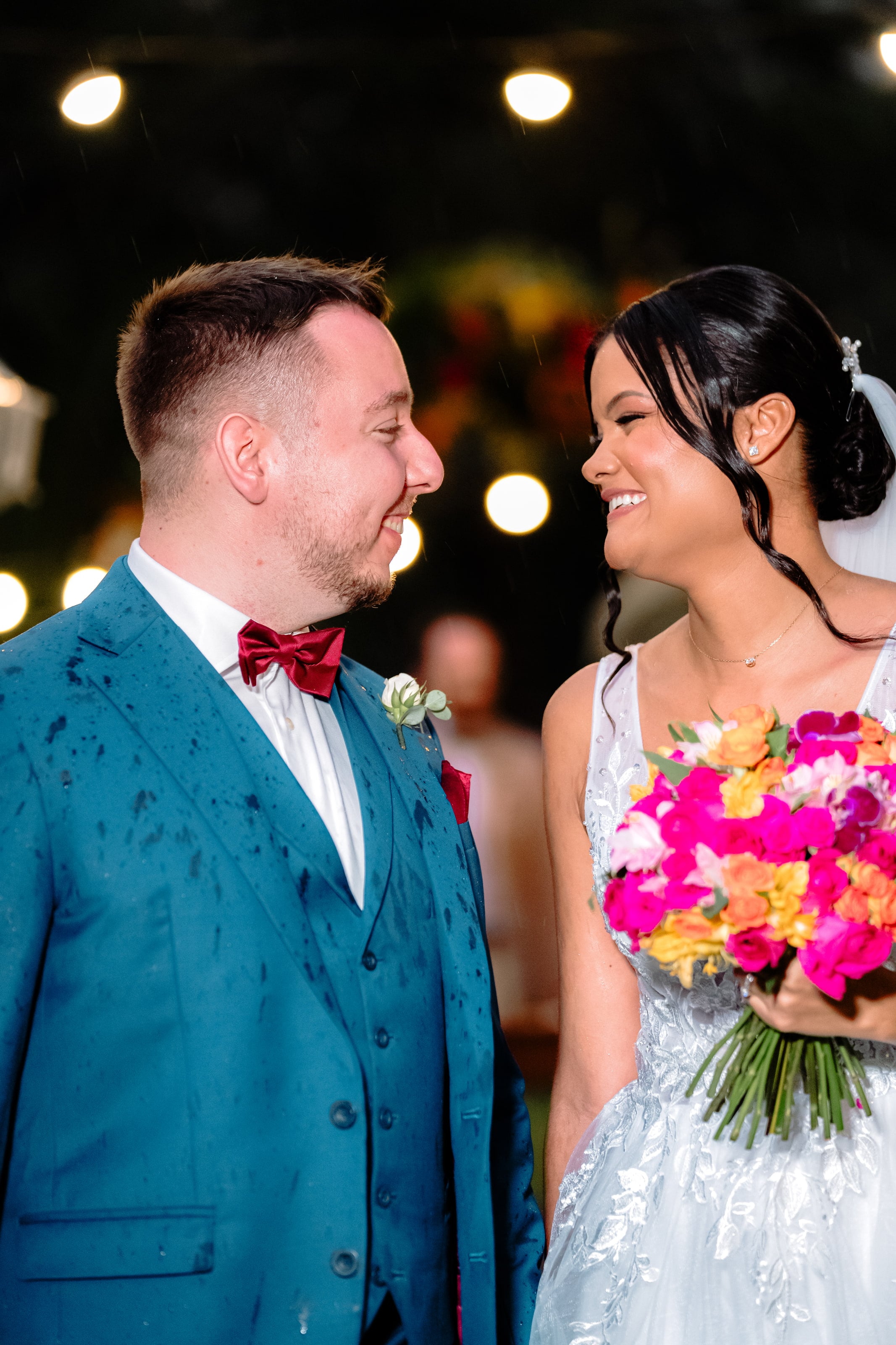 Casal sorrindo, com gotas de chuva no terno do noivo, casamento de J & K