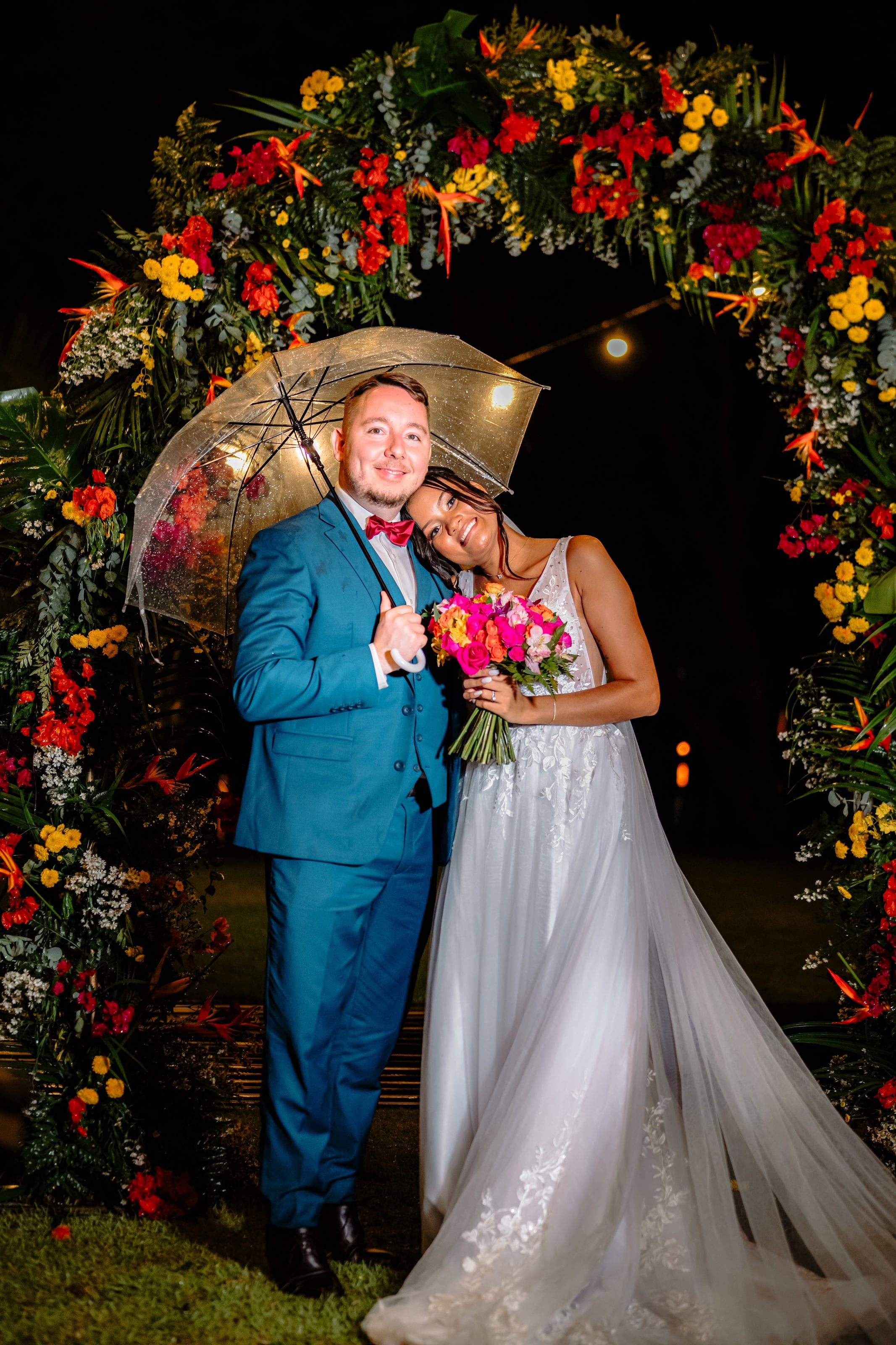 Casal sob o guarda-chuva no arco de flores tropicais, casamento de J & K
