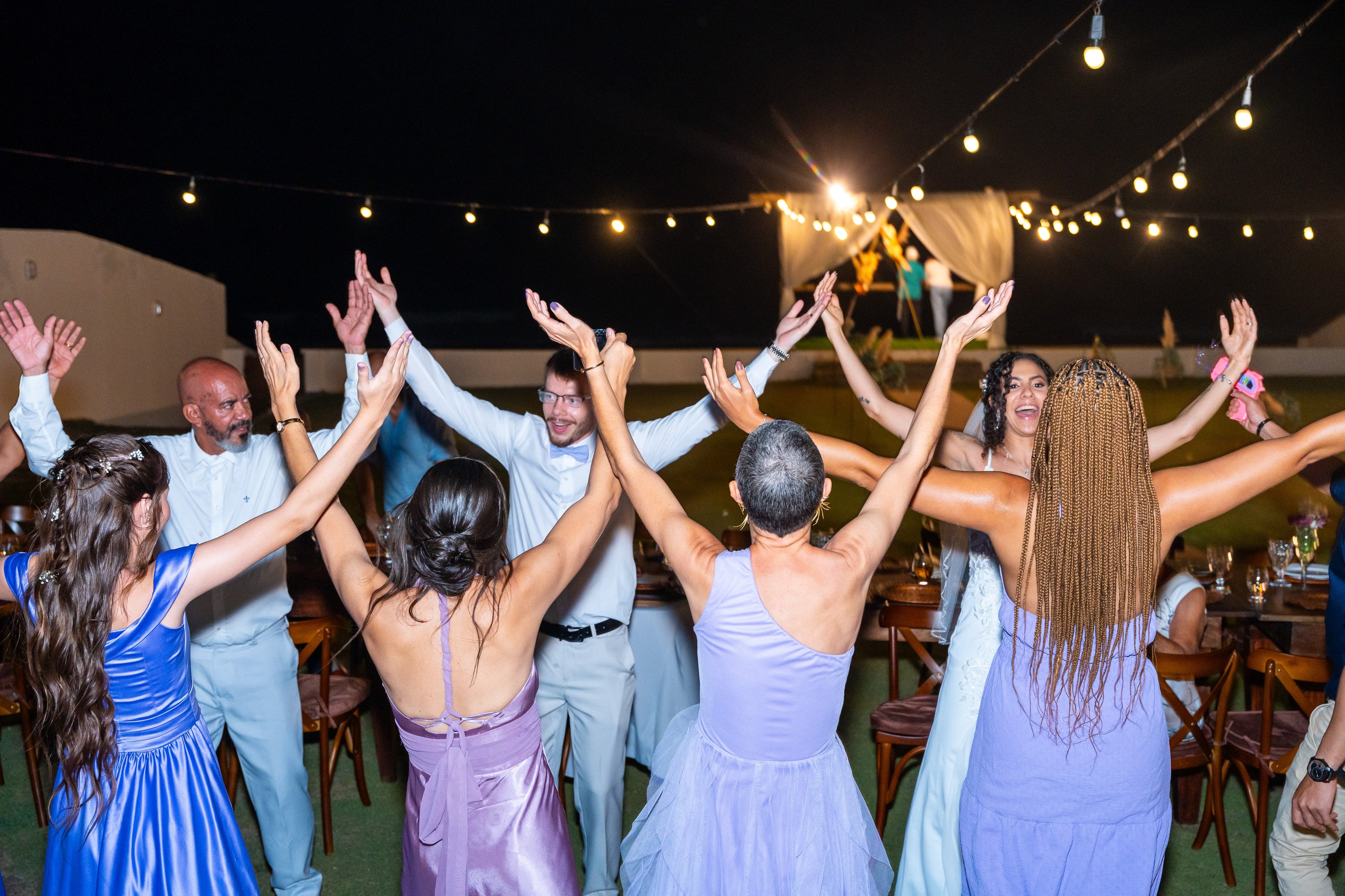 Convidados de braços para cima na pista, sob o varal de luzes, casamento de L & M em Salvador