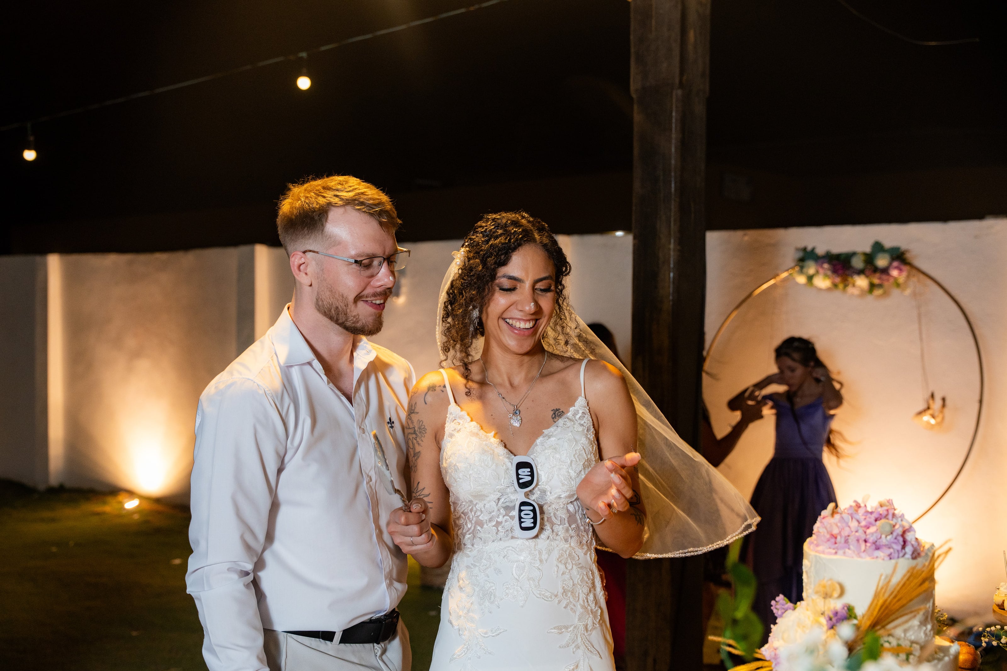 Casal à noite ao lado da mesa do bolo, casamento de L & M em Salvador