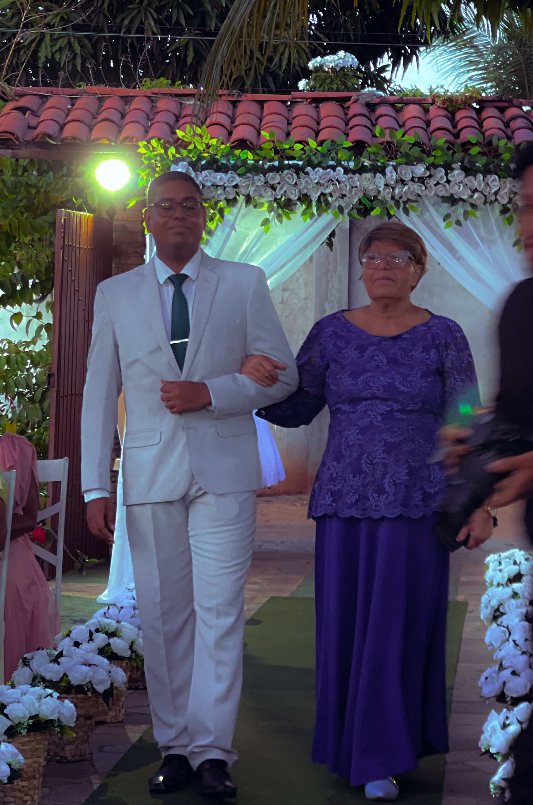 Cortejo de entrada no jardim, entre cadeiras brancas e flores, casamento de M & I