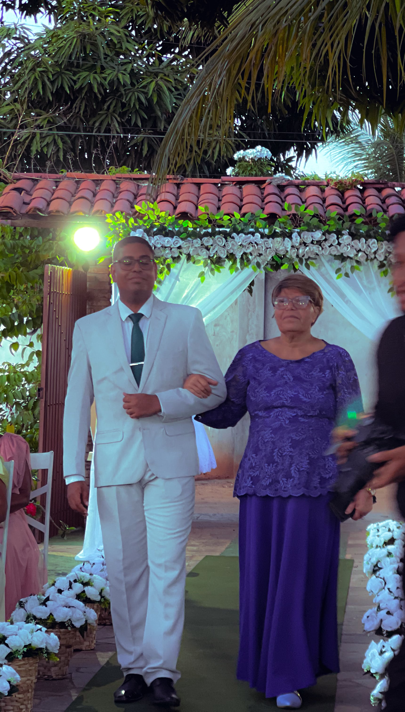 Cortejo de entrada no jardim, entre cadeiras brancas e flores, casamento de M & I