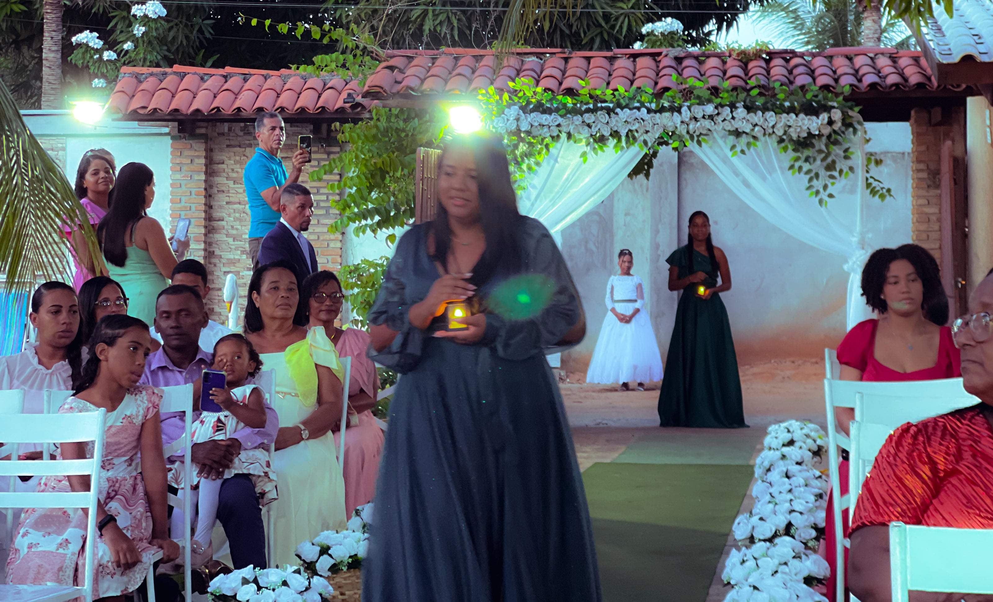 Cortejo de entrada no jardim, entre cadeiras brancas e flores, casamento de M & I