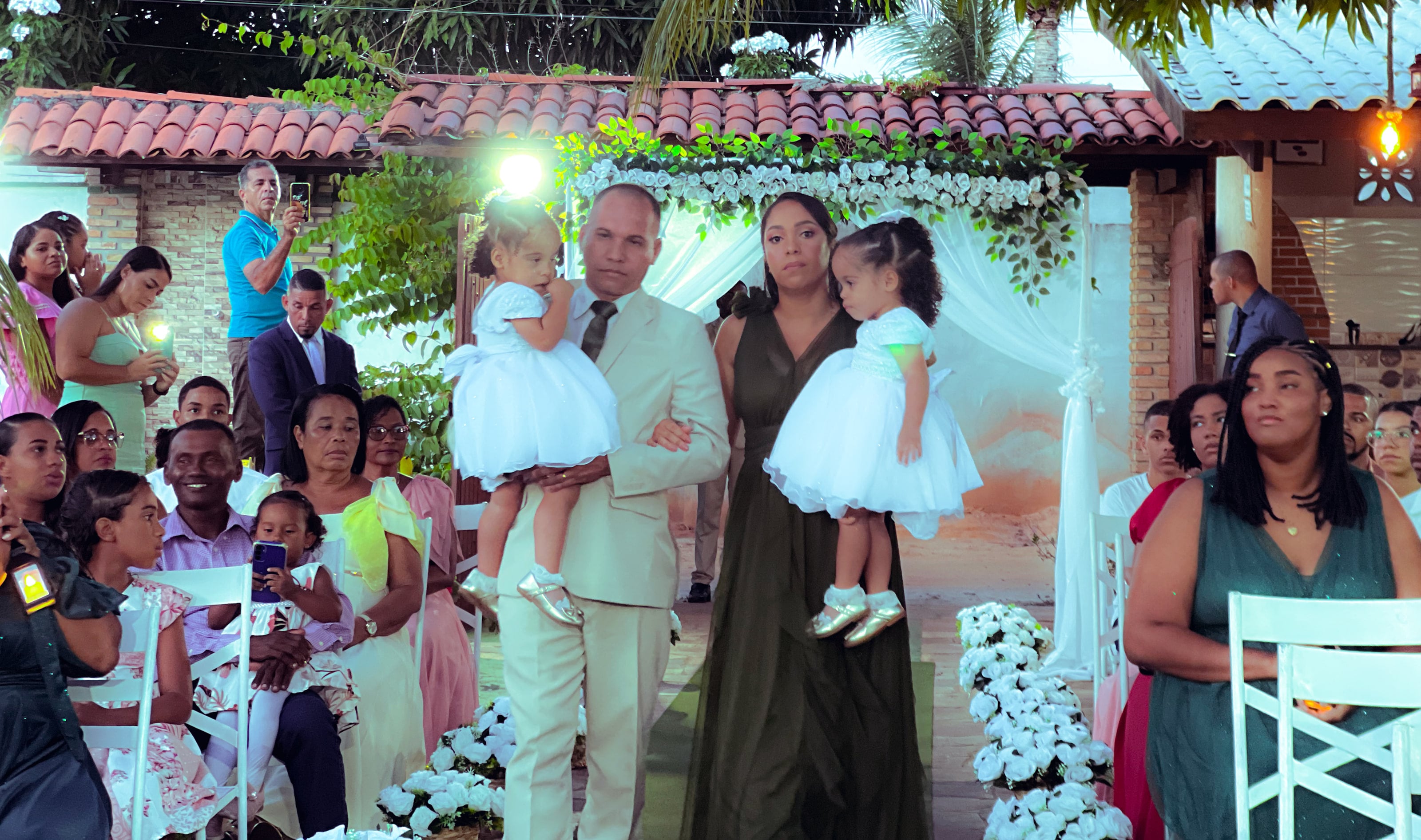 Cortejo de entrada no jardim, entre cadeiras brancas e flores, casamento de M & I