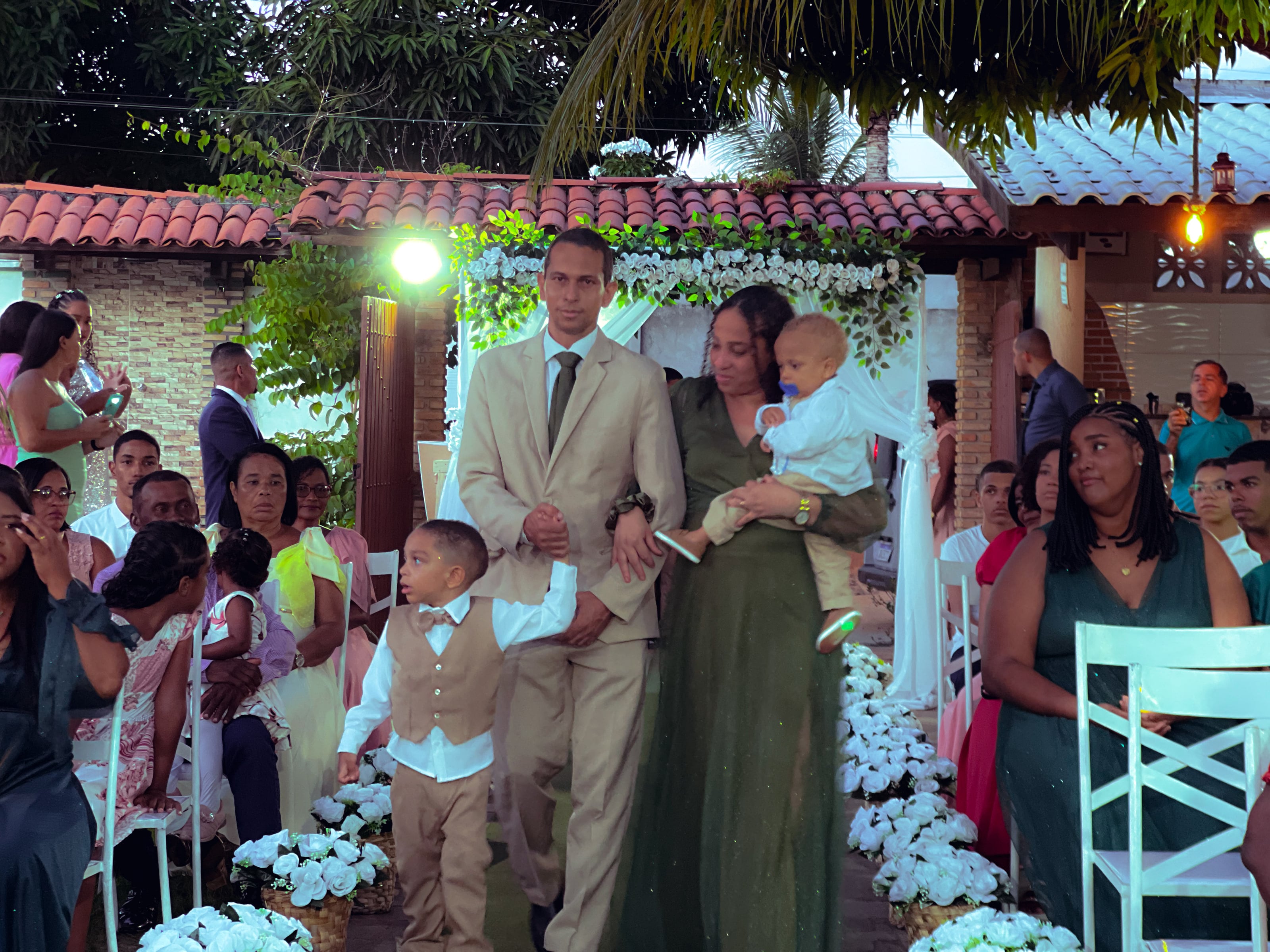 Cortejo de entrada no jardim, entre cadeiras brancas e flores, casamento de M & I