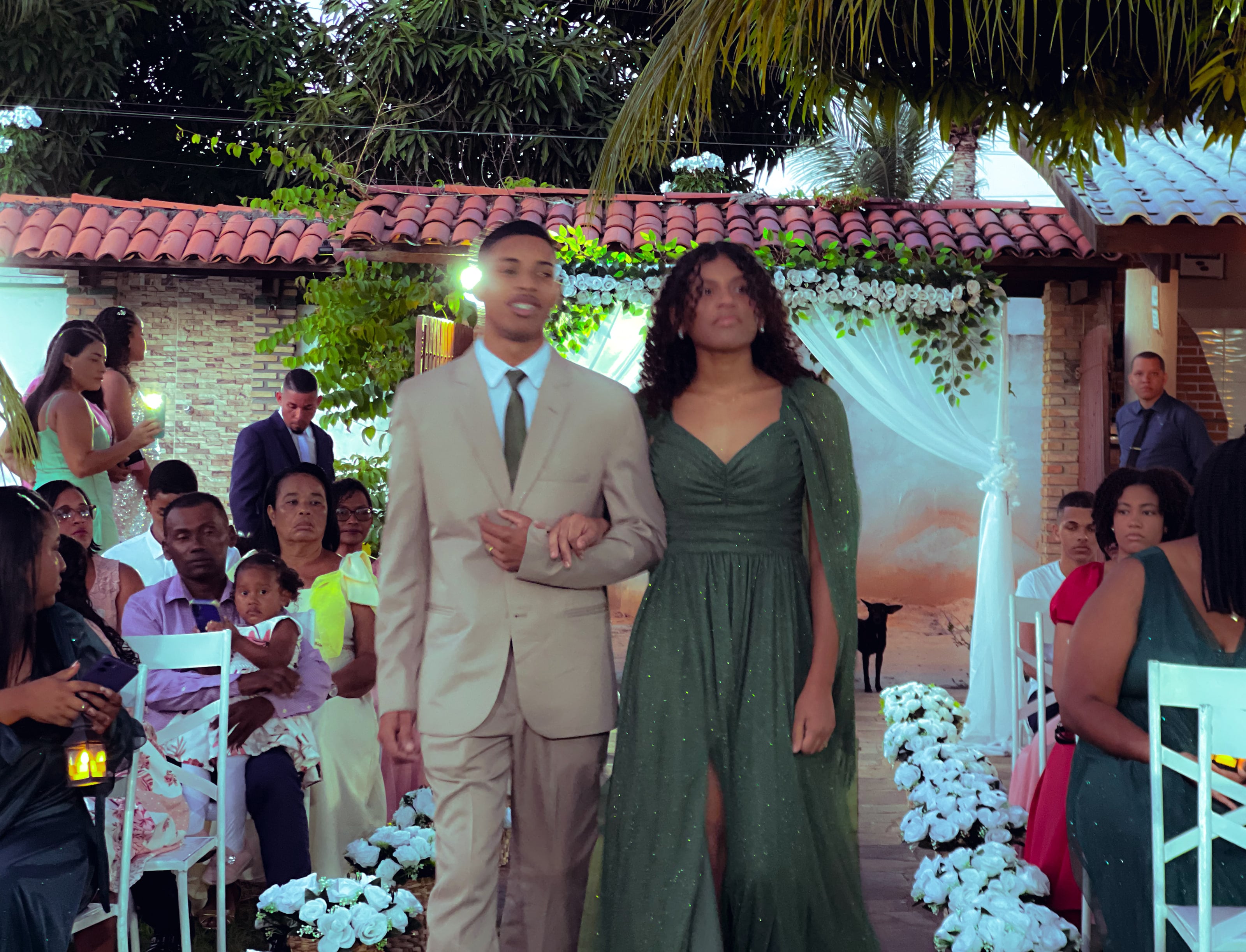 Cortejo de entrada no jardim, entre cadeiras brancas e flores, casamento de M & I