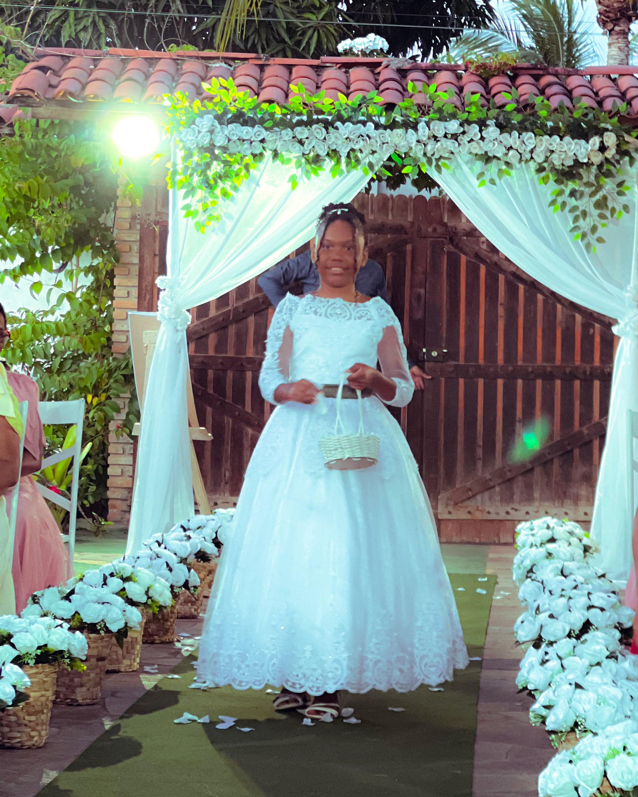 Daminha de vestido branco com cesta de pétalas no corredor, casamento de M & I