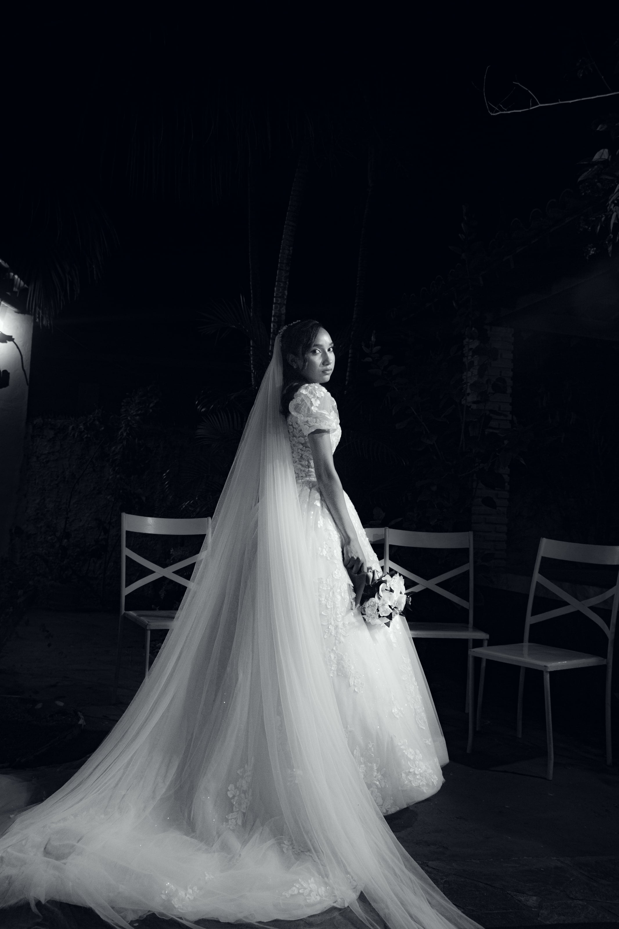 Noiva com o véu longo e o buquê no jardim à noite, casamento de M & I