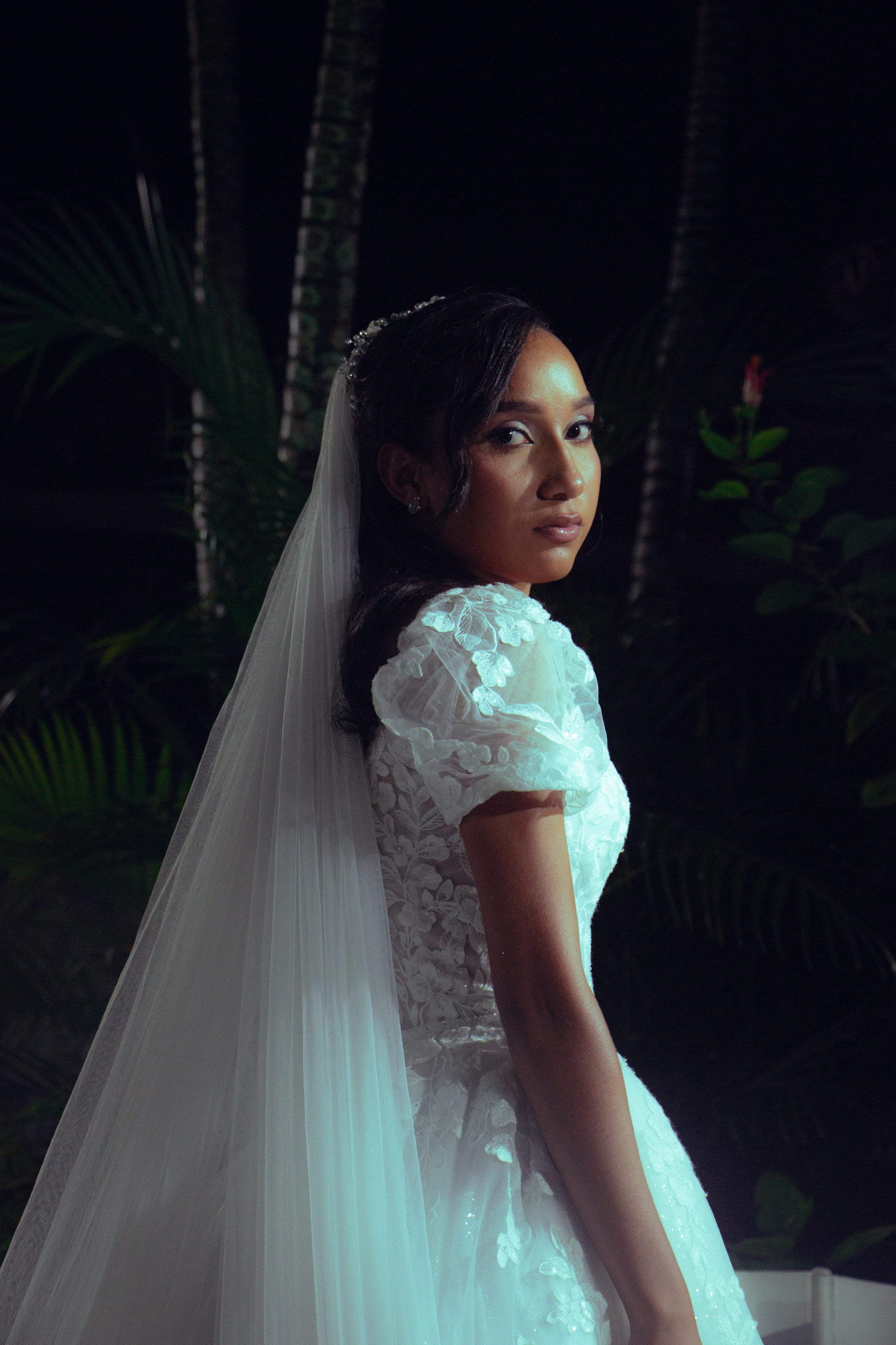 Noiva com o véu longo e o buquê no jardim à noite, casamento de M & I