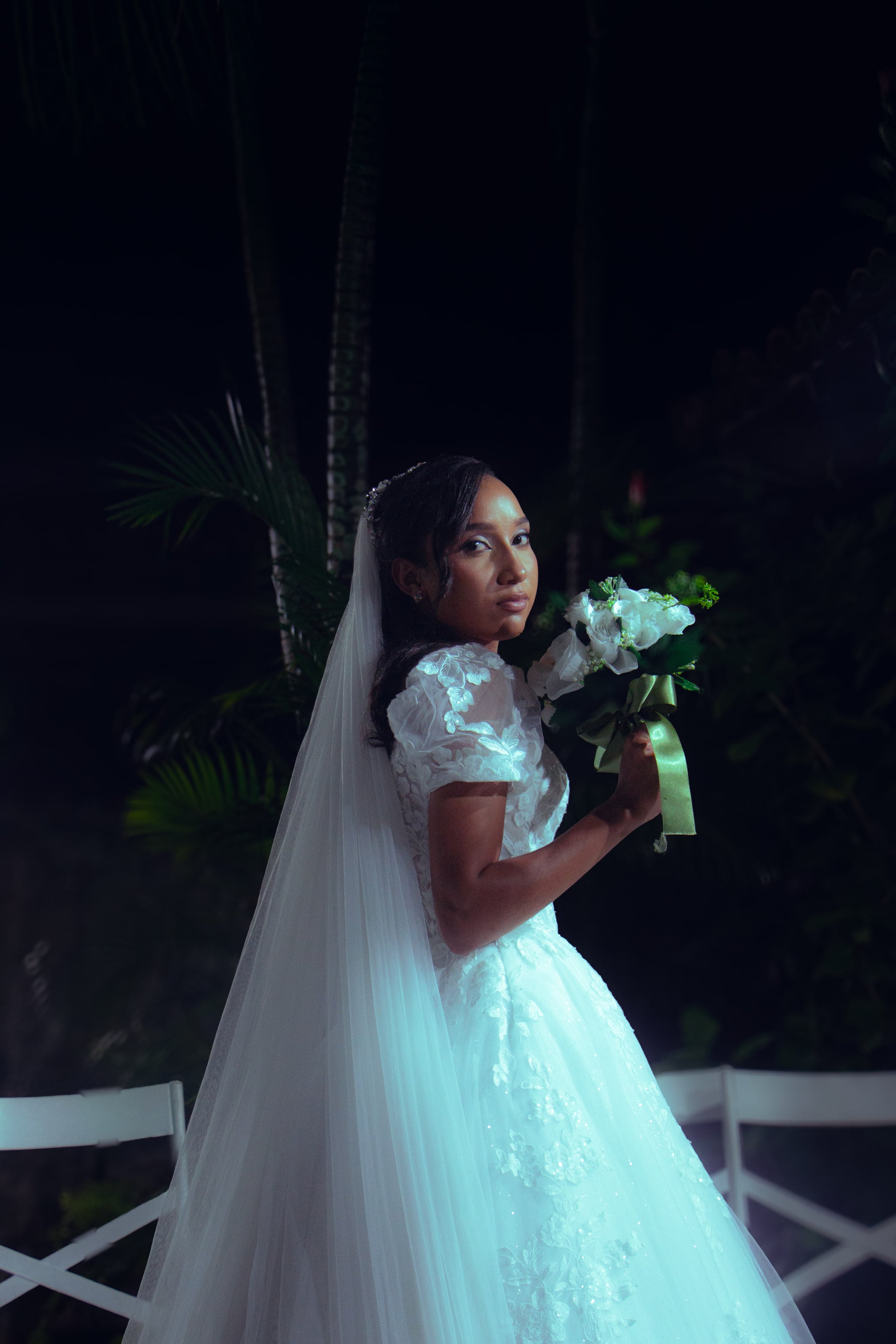 Noiva com o véu longo e o buquê no jardim à noite, casamento de M & I