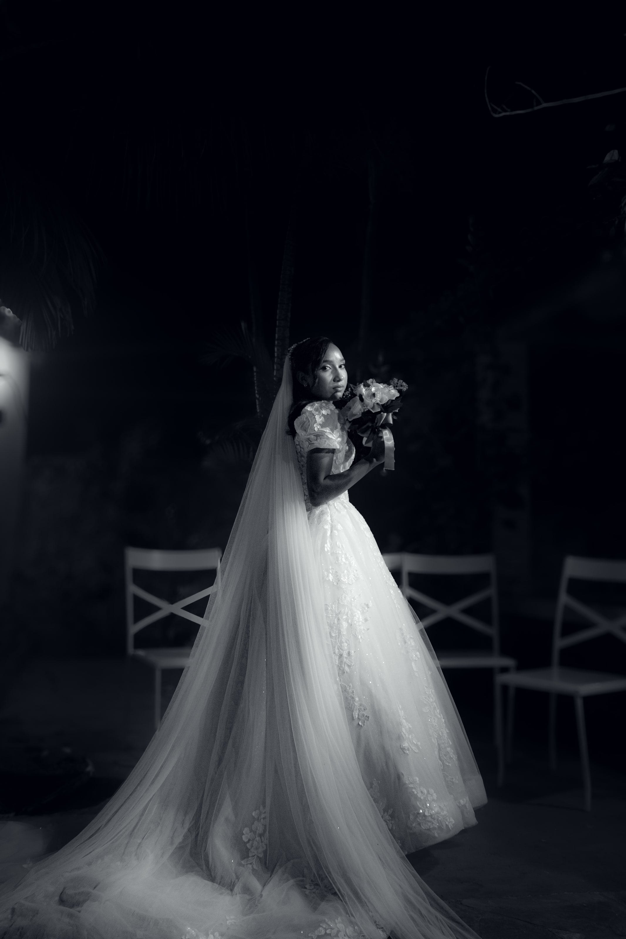 Noiva com o véu longo e o buquê no jardim à noite, casamento de M & I
