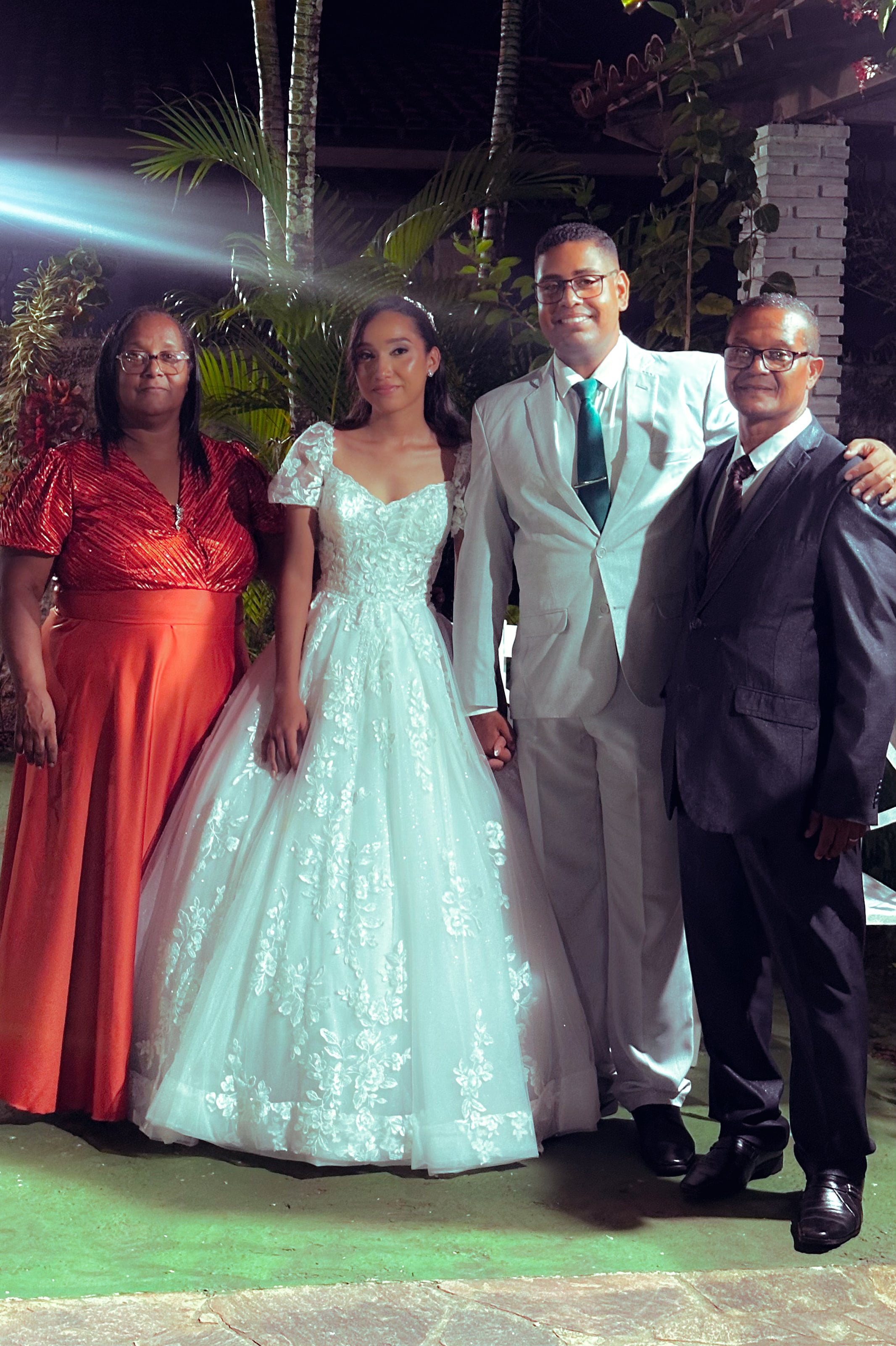 Noiva e noivo com familiares no jardim, à noite, casamento de M & I