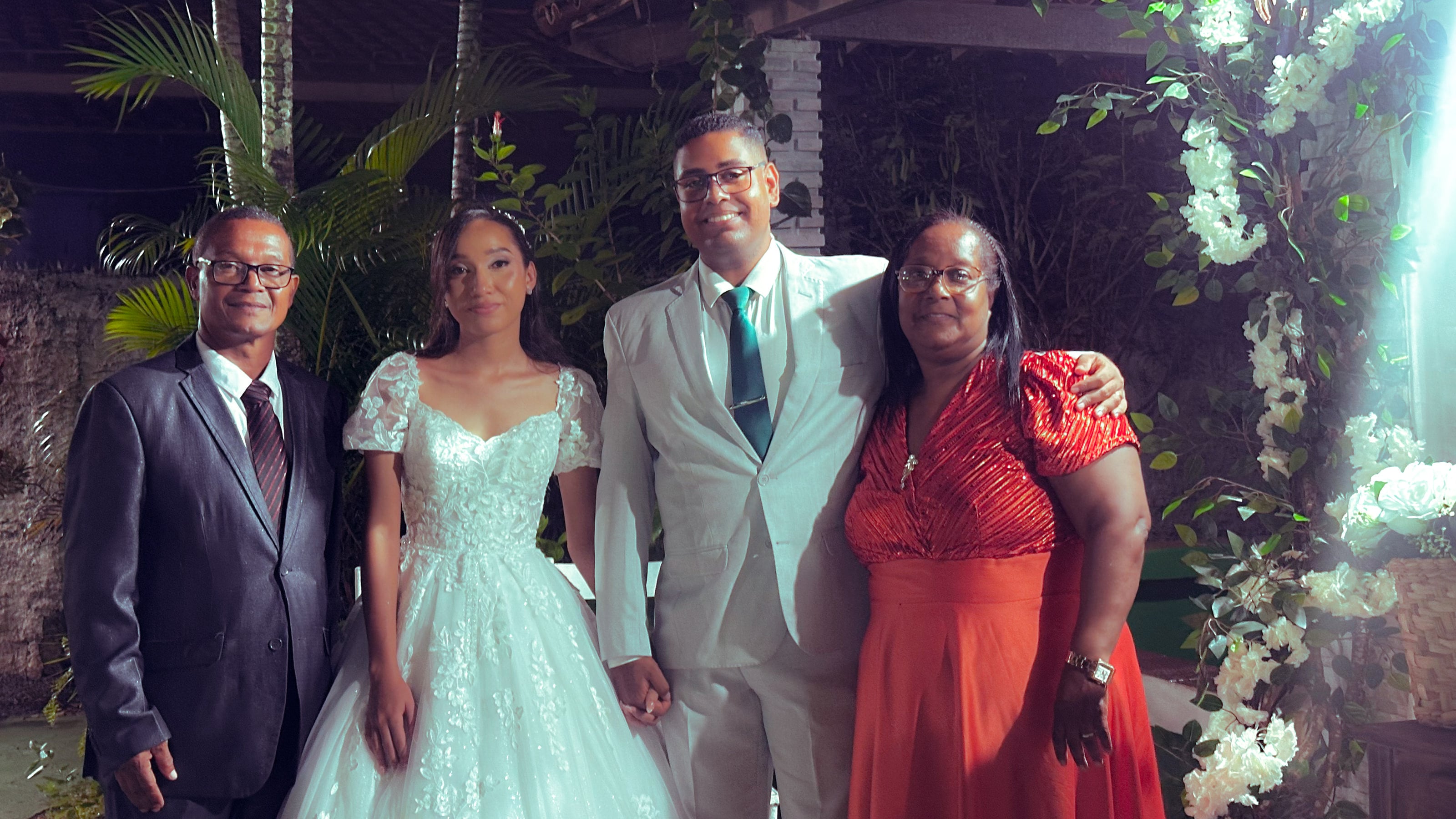 Noiva e noivo com familiares no jardim, à noite, casamento de M & I
