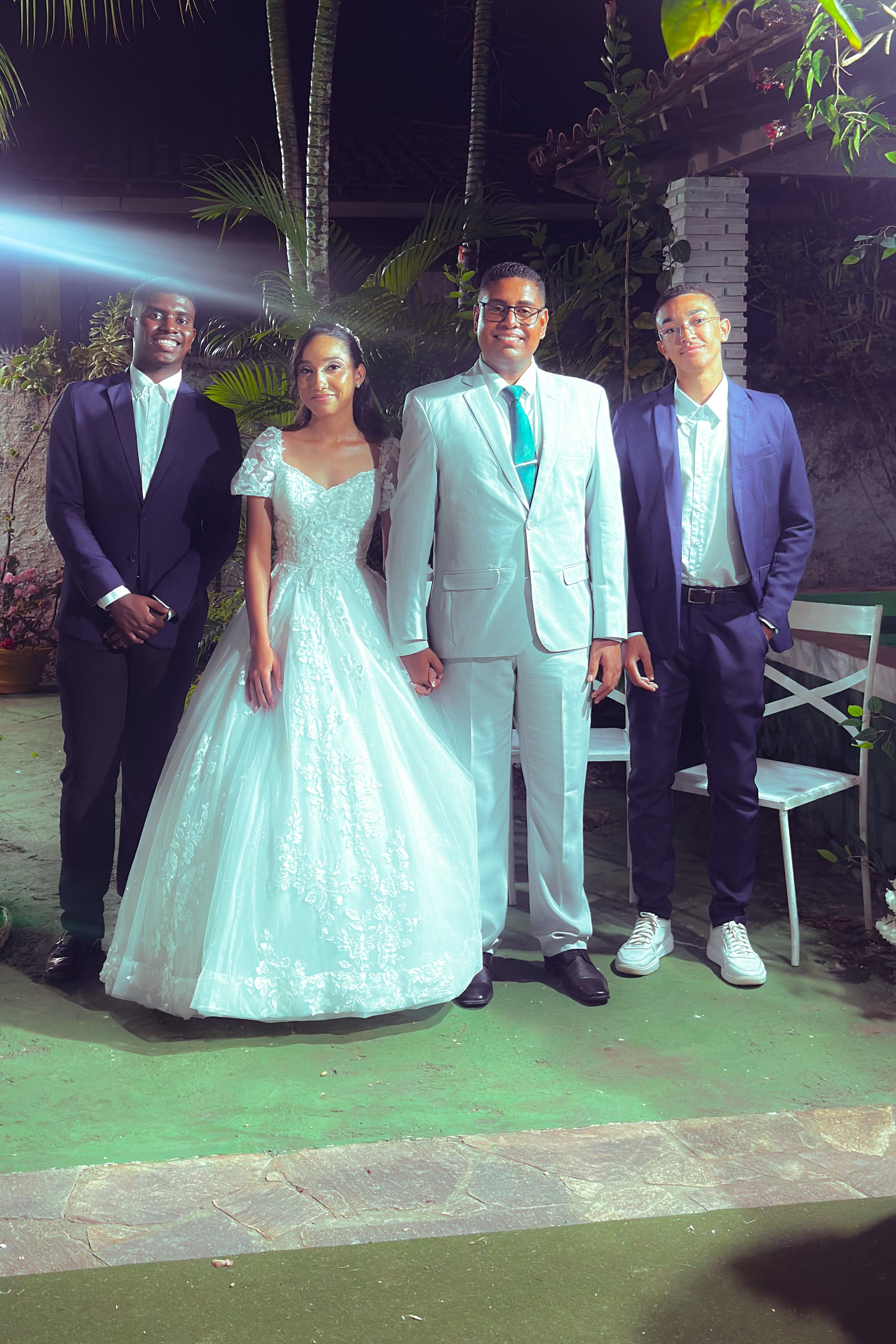Noiva e noivo com familiares no jardim, à noite, casamento de M & I