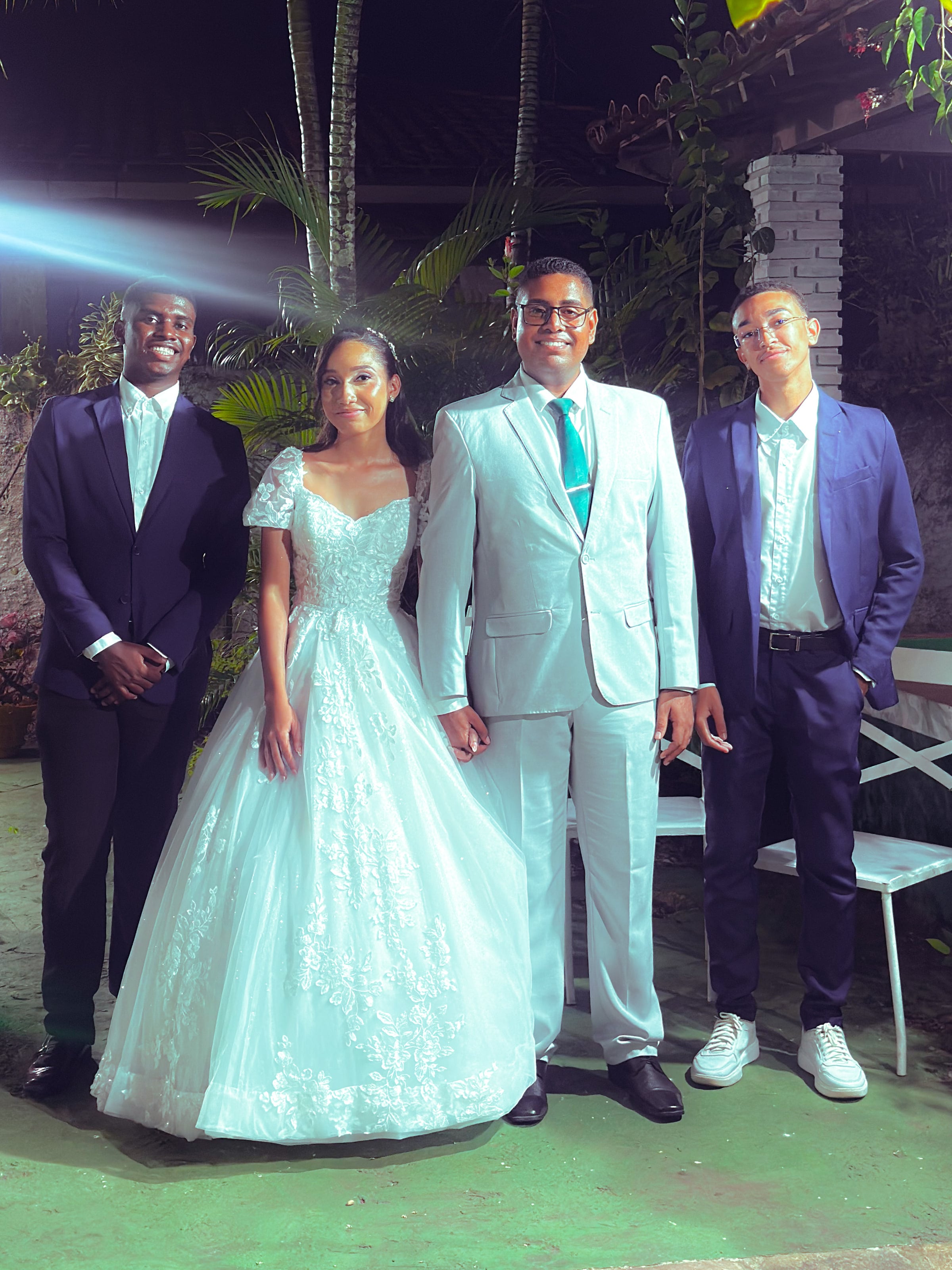 Noiva e noivo com familiares no jardim, à noite, casamento de M & I
