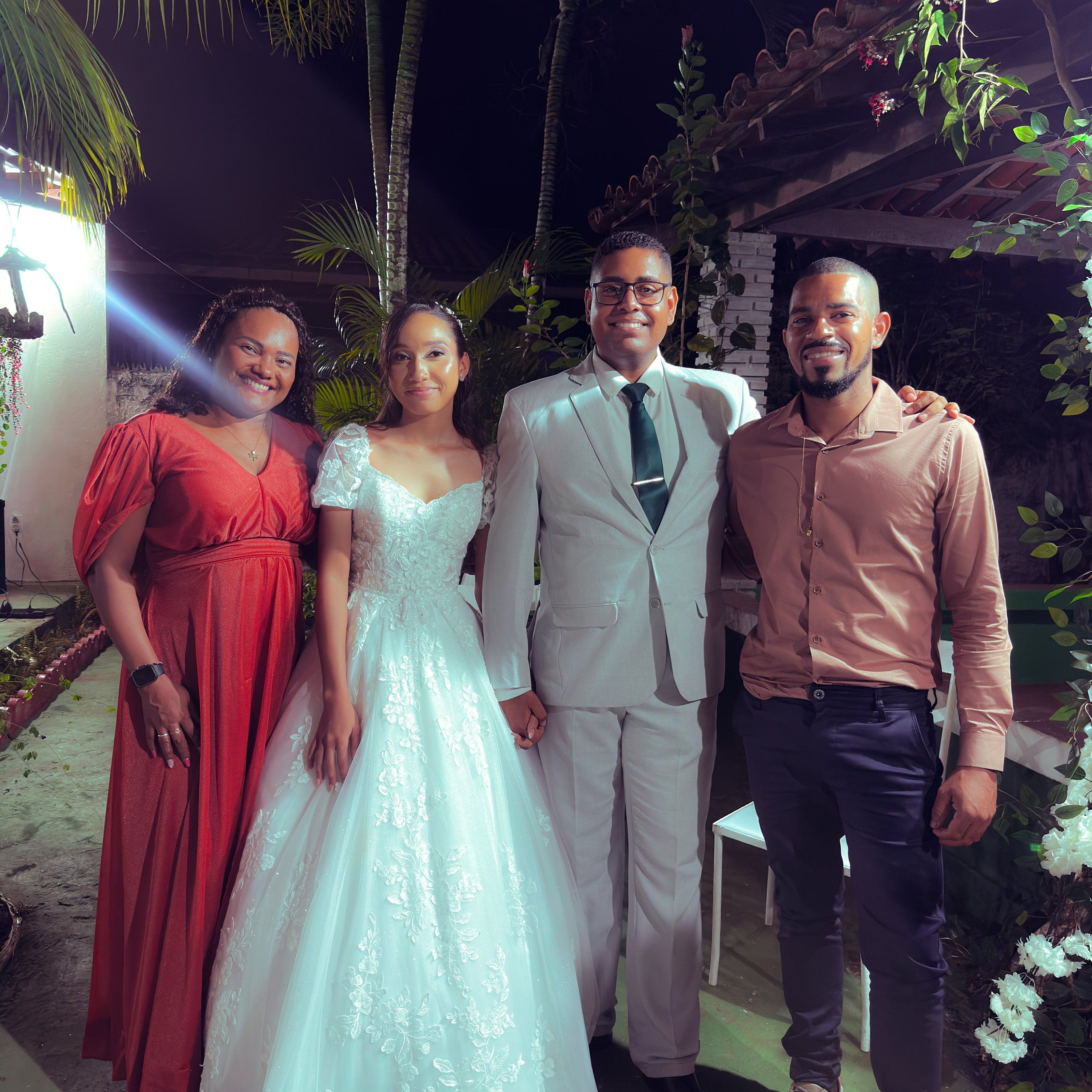 Noiva e noivo com familiares no jardim, à noite, casamento de M & I