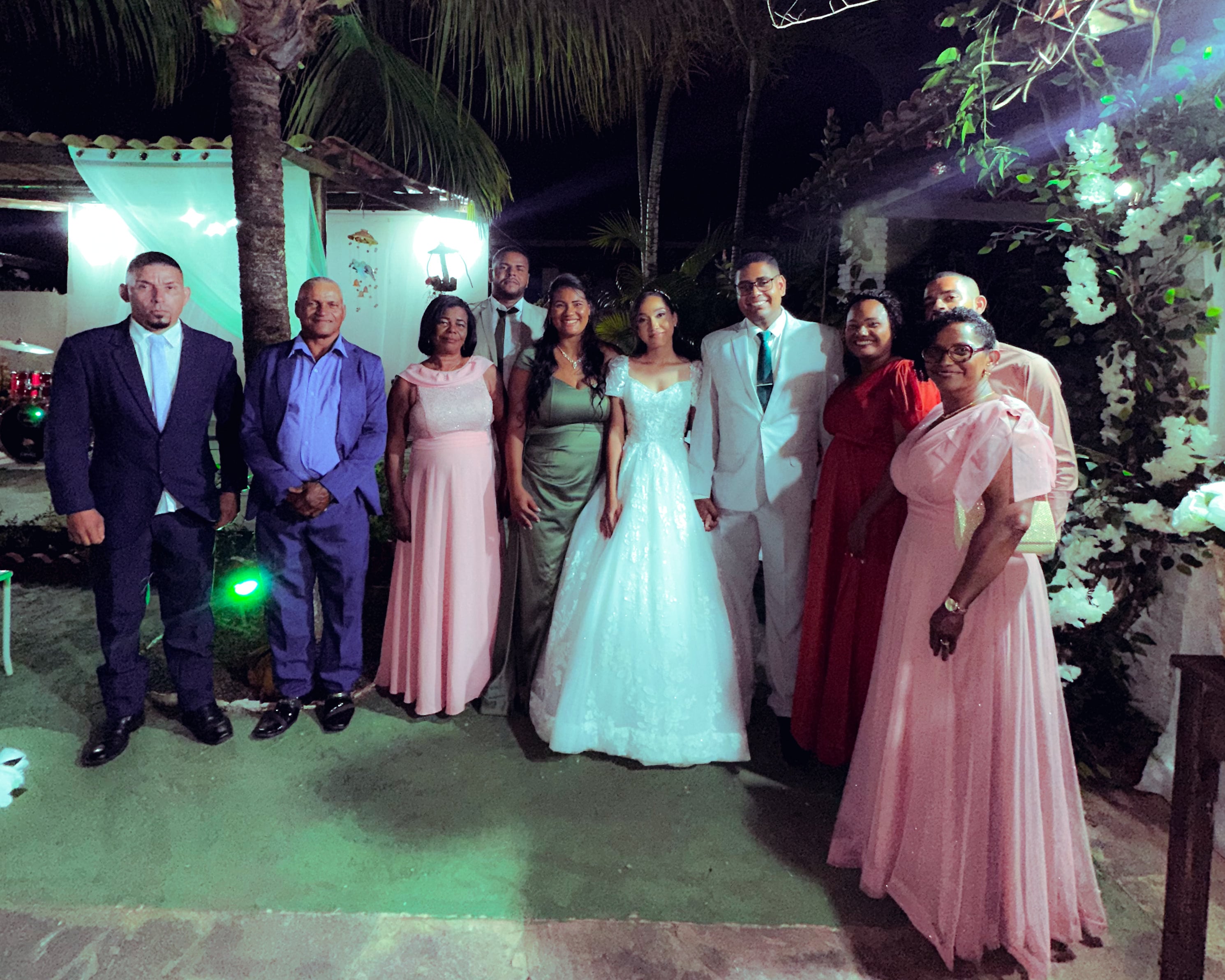 Noiva e noivo com familiares no jardim, à noite, casamento de M & I
