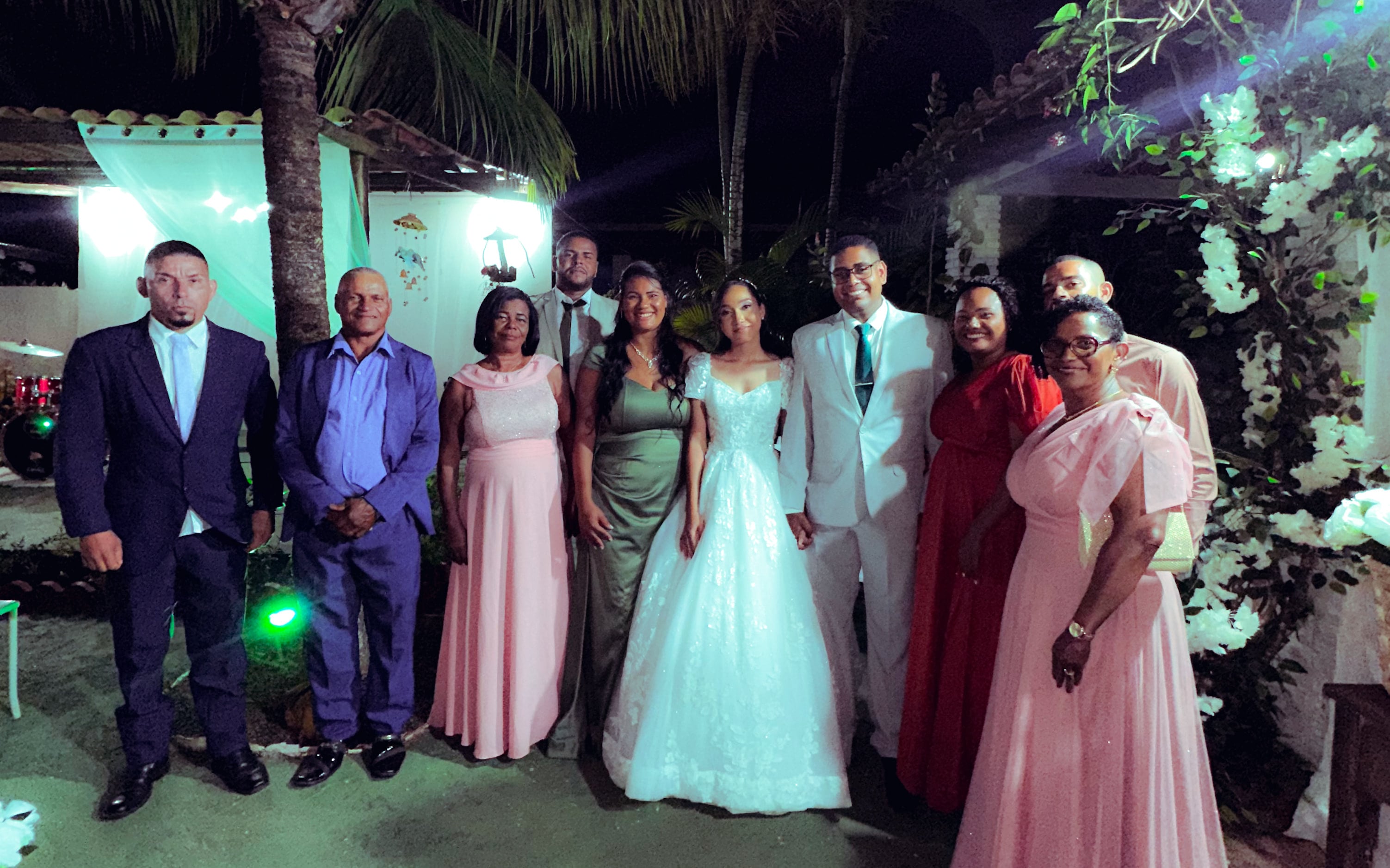 Noiva e noivo com familiares no jardim, à noite, casamento de M & I