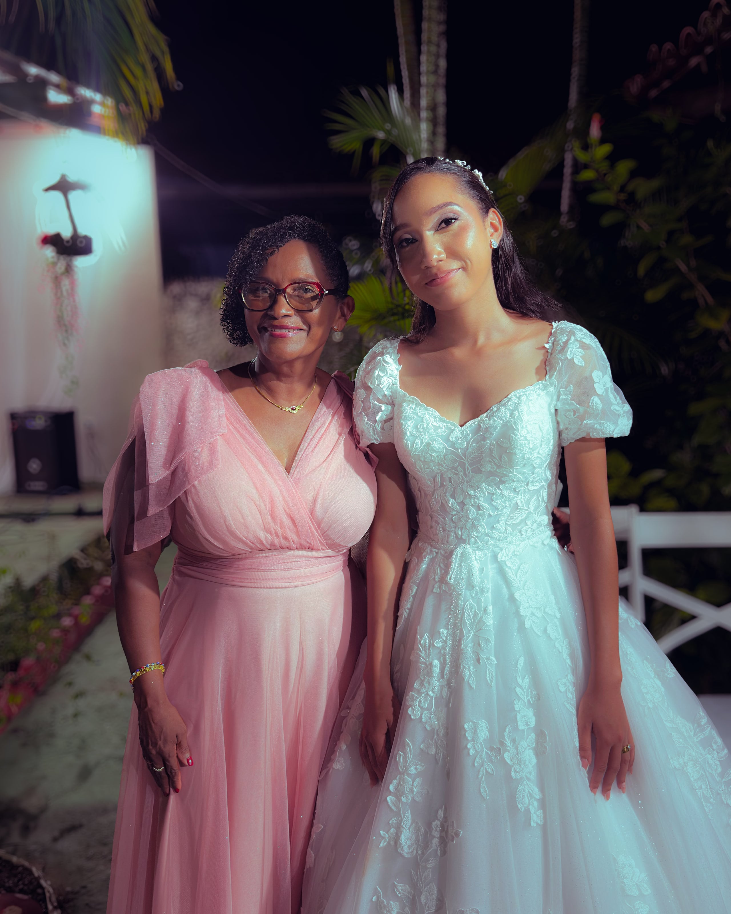 Noiva e noivo com convidados no jardim, à noite, casamento de M & I
