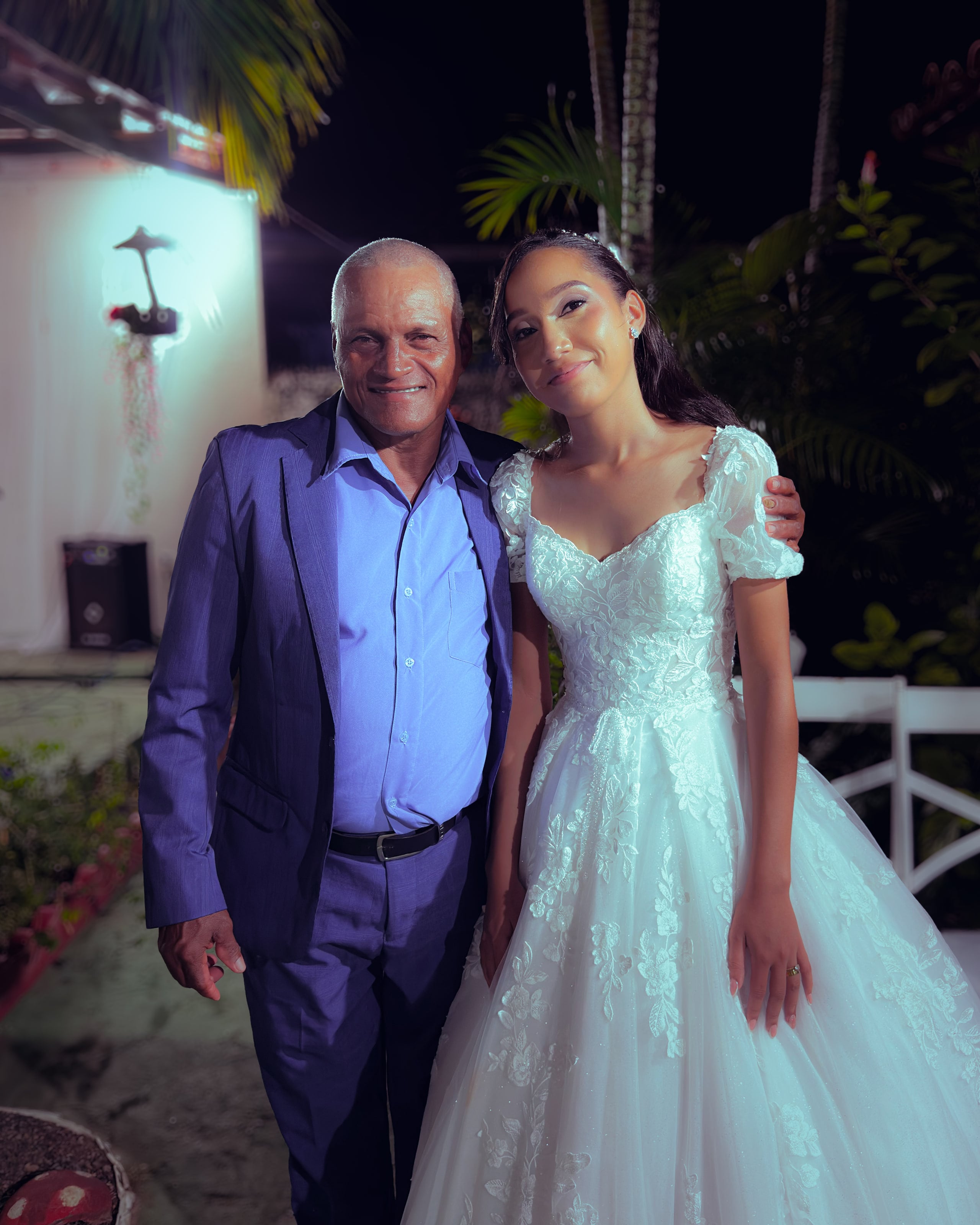 Noiva e noivo com convidados no jardim, à noite, casamento de M & I