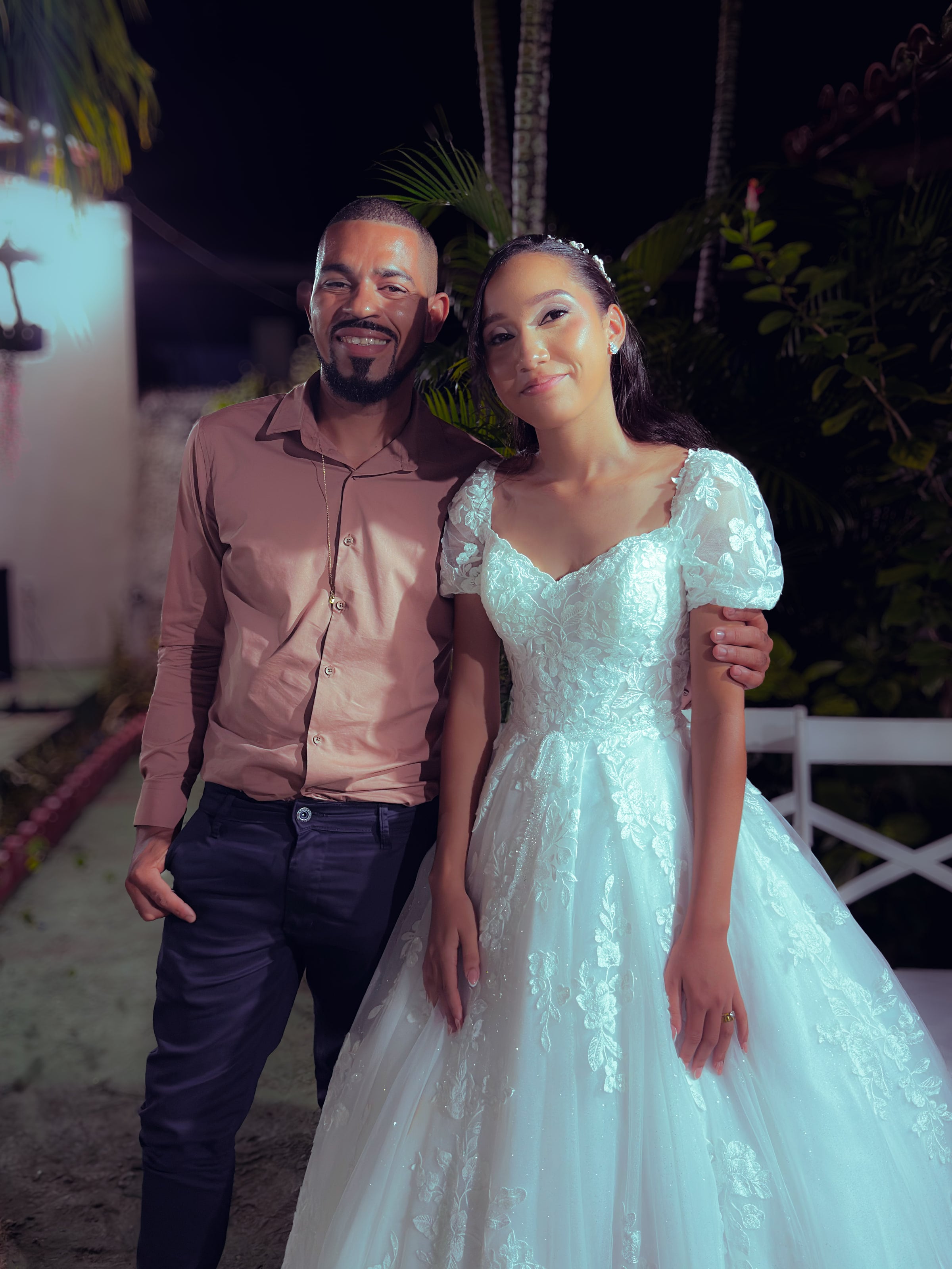 Noiva e noivo com convidados no jardim, à noite, casamento de M & I