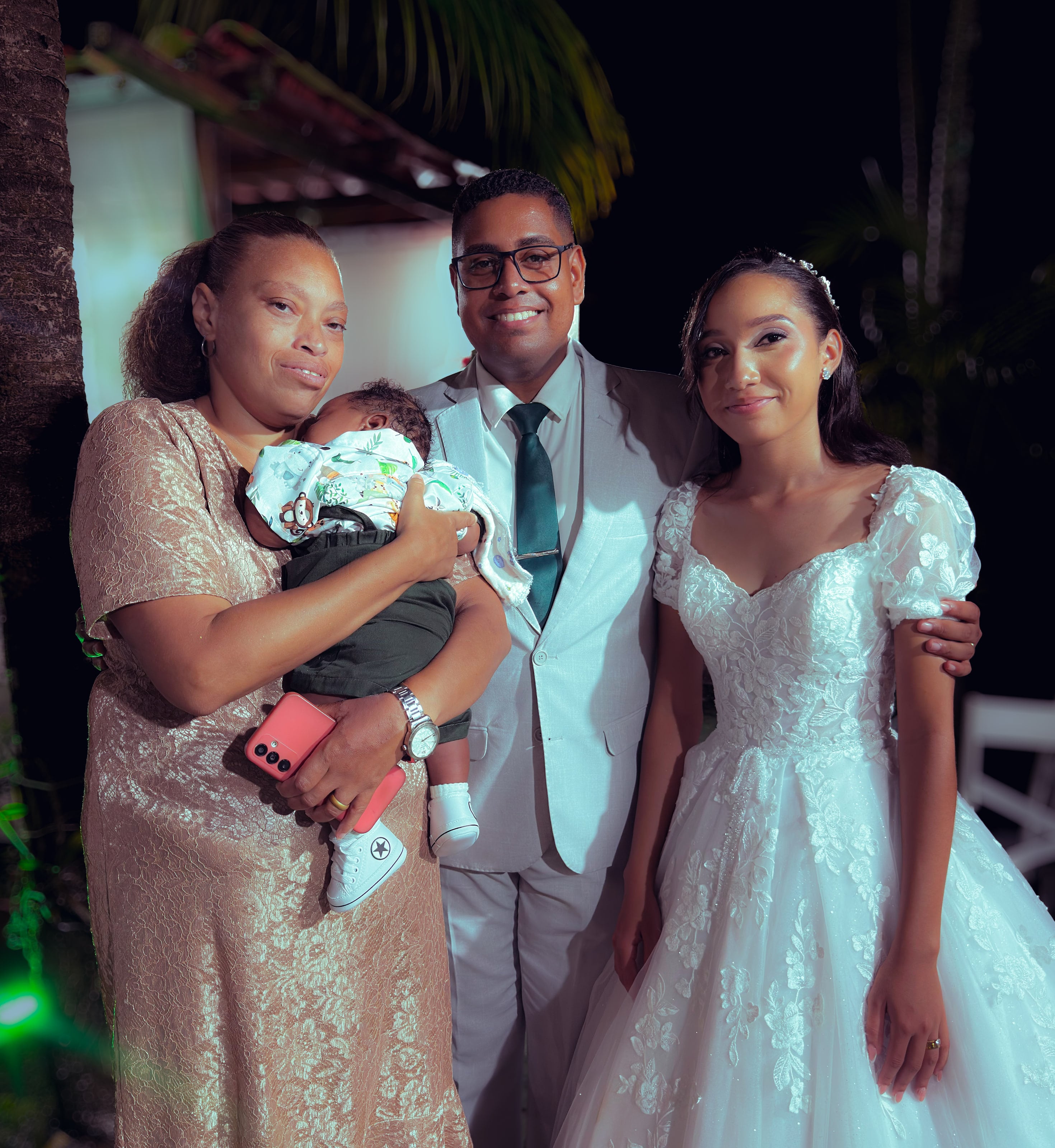 Noiva e noivo com convidados no jardim, à noite, casamento de M & I