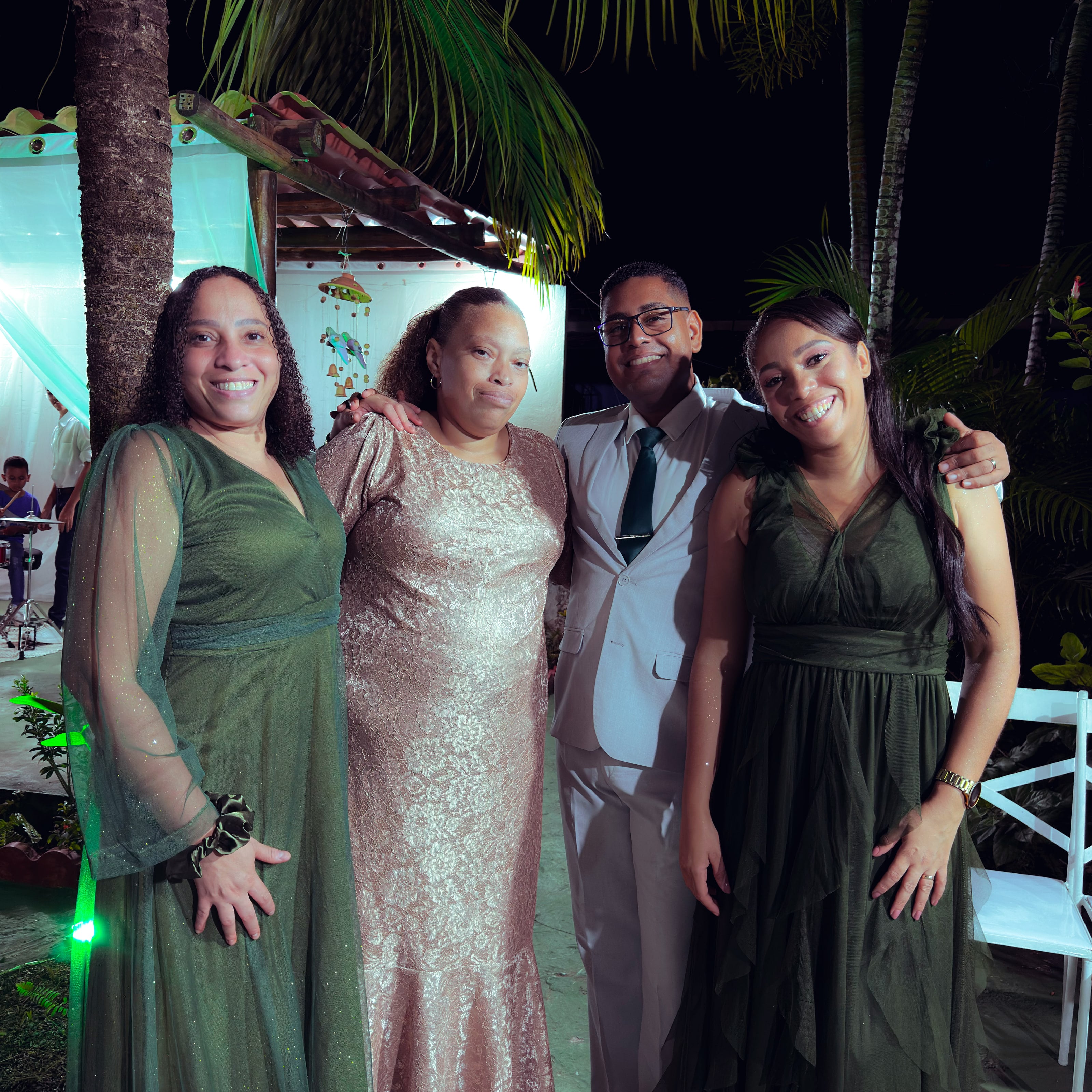 Noiva e noivo com convidados no jardim, à noite, casamento de M & I