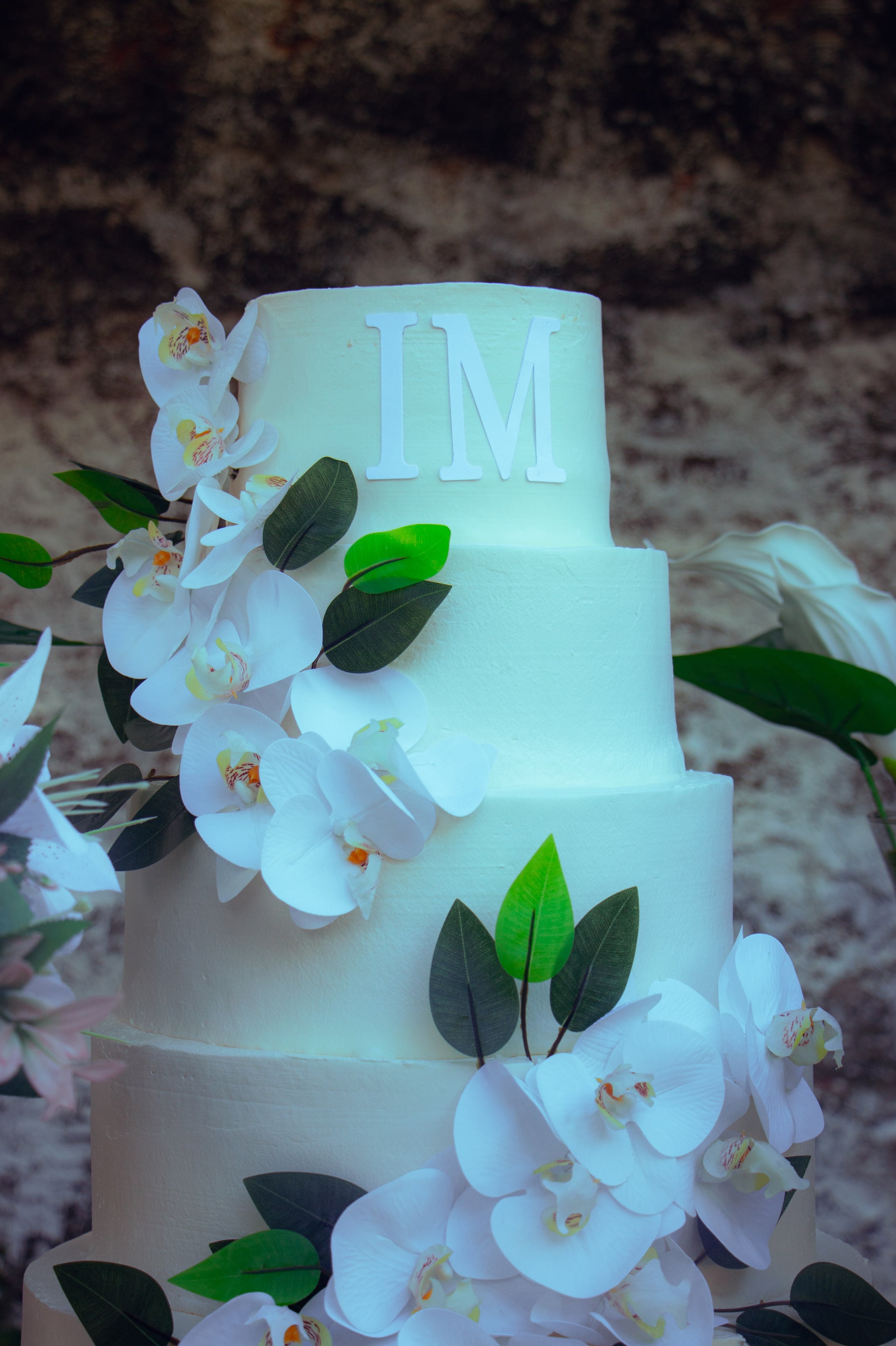 Bolo de três andares com orquídeas e as iniciais do casal, casamento de M & I