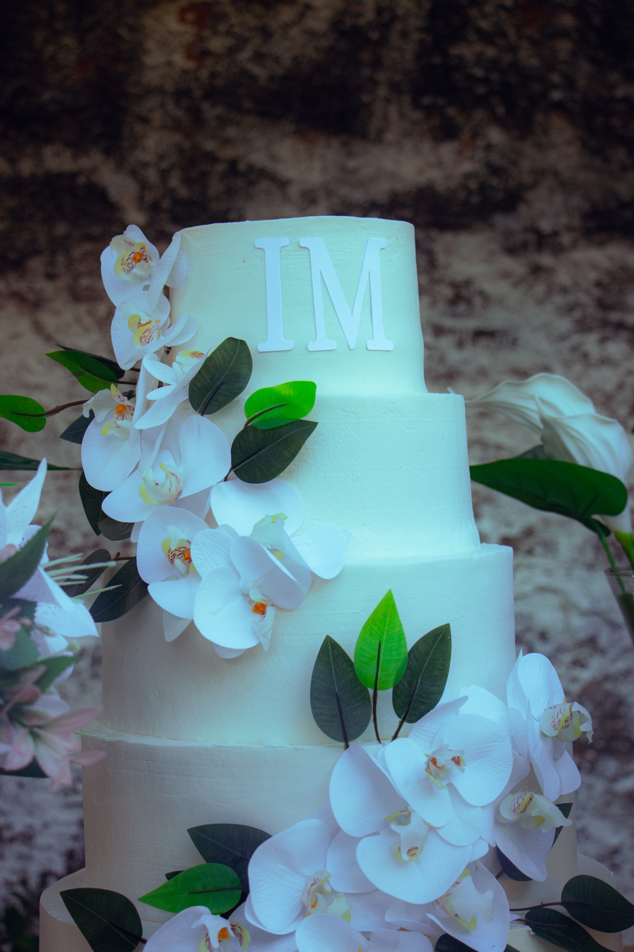 Bolo de três andares com orquídeas e as iniciais do casal, casamento de M & I