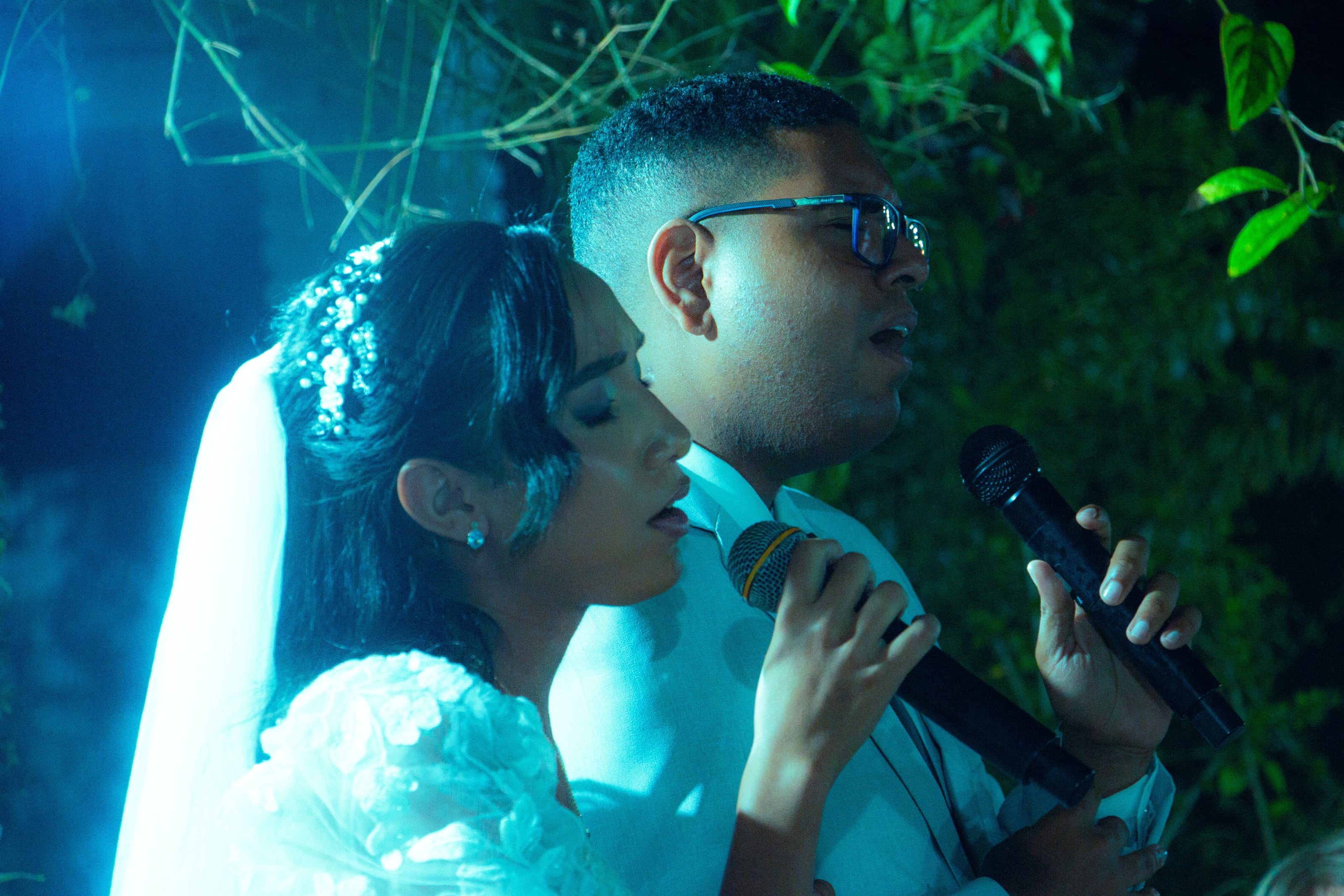 Casal canta ao microfone durante a cerimônia, casamento de M & I