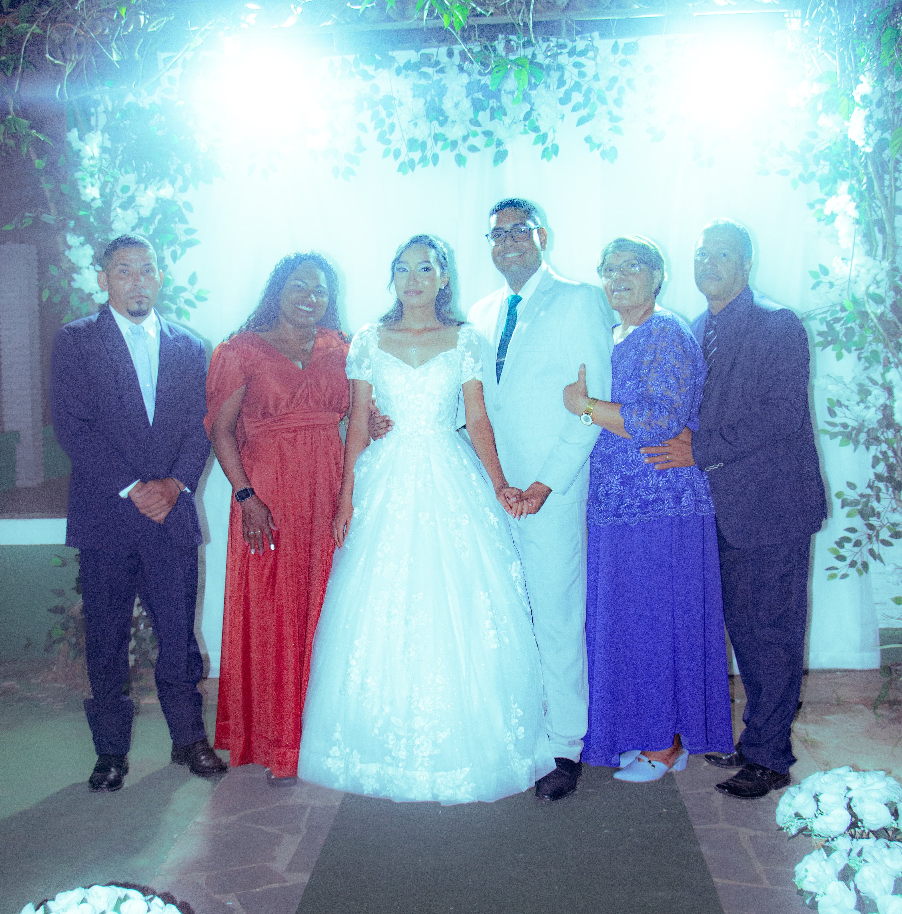 Casal com familiares diante da cortina branca, casamento de M & I