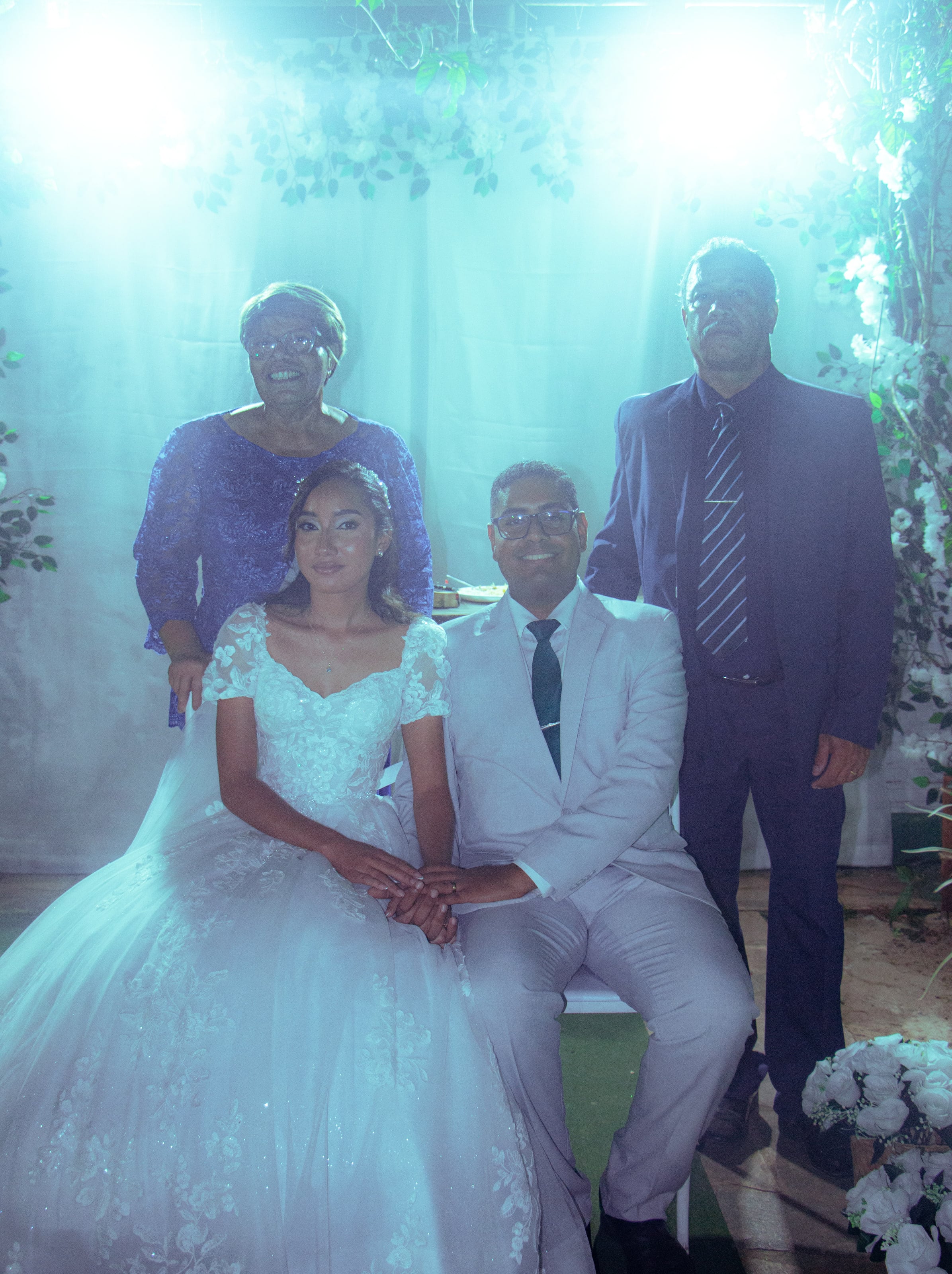 Casal com familiares diante da cortina branca, casamento de M & I