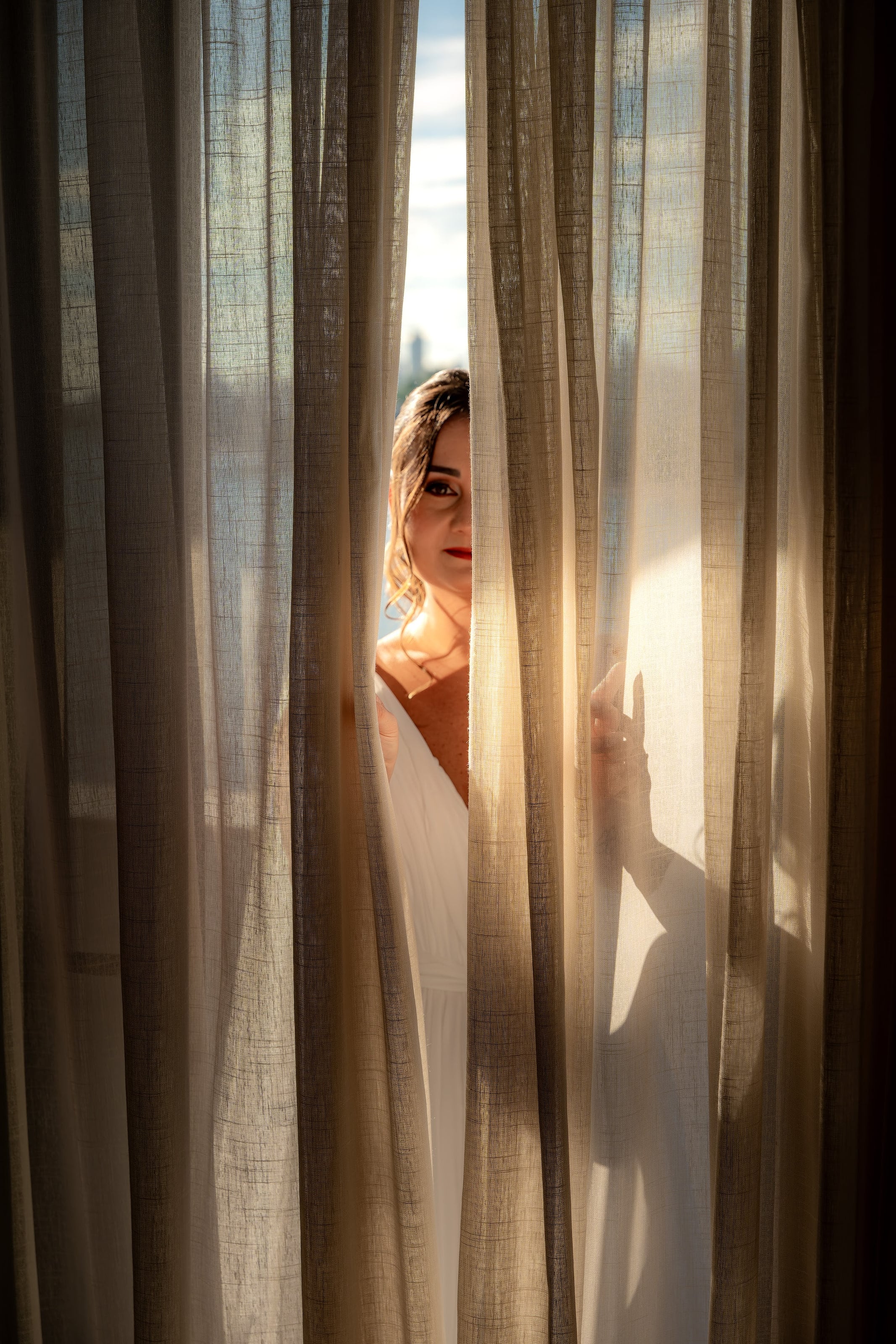 Noiva entre cortinas de linho na luz da manhã, casamento de N & H