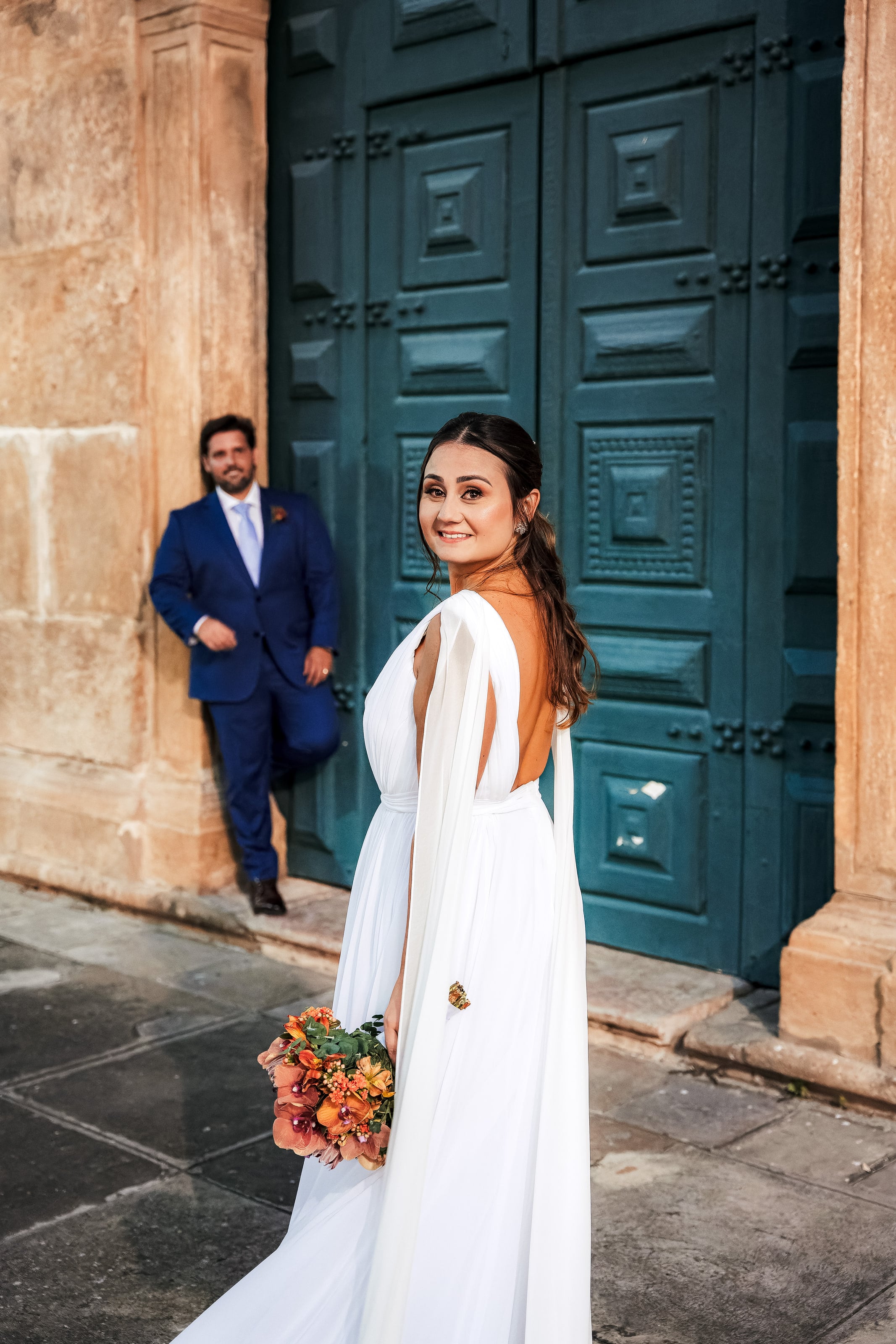 Casal diante da porta verde de uma igreja antiga, casamento de N & H