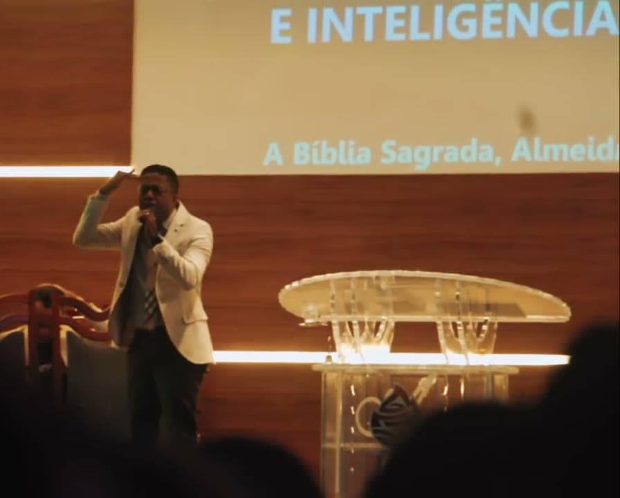 Palestrante no palco diante do telão, congresso de jovens filmado pela Duat